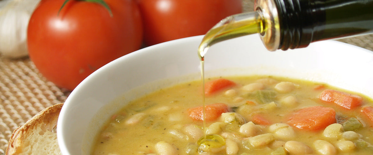 olive oil pouring out of bottle into soup