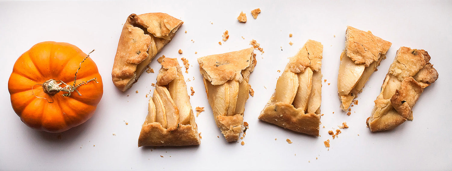Slices of rustic apple galette beside a small orange pumpkin.