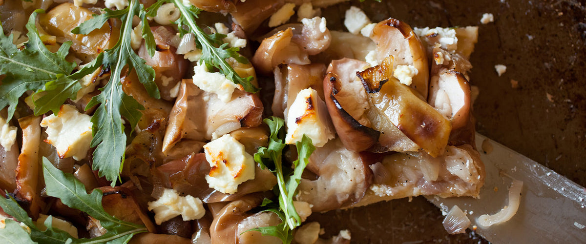 Savory apple and goat cheese tart topped with caramelized onions and fresh arugula.