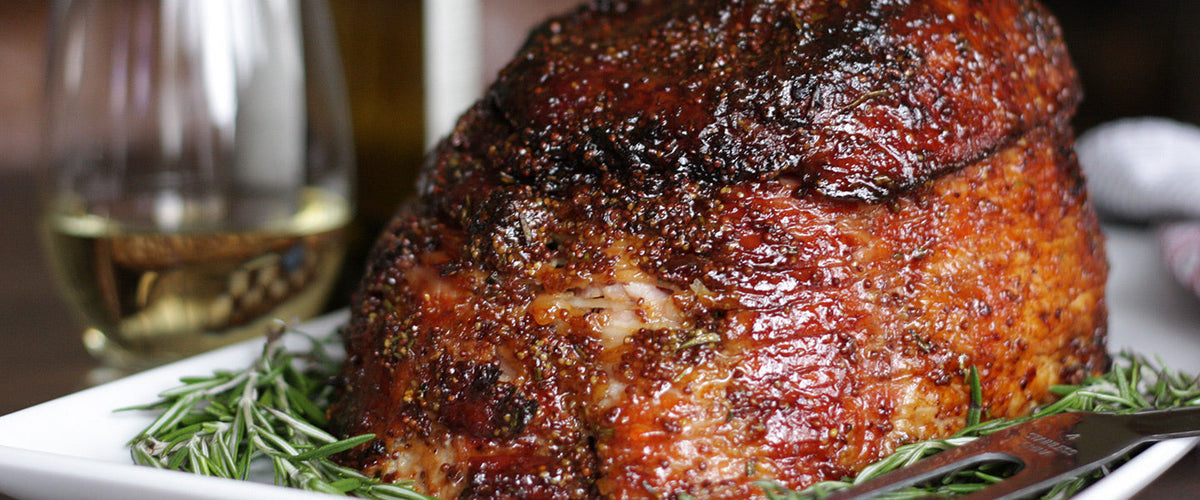 Baked Easter ham seasoned with herbs and mustard.