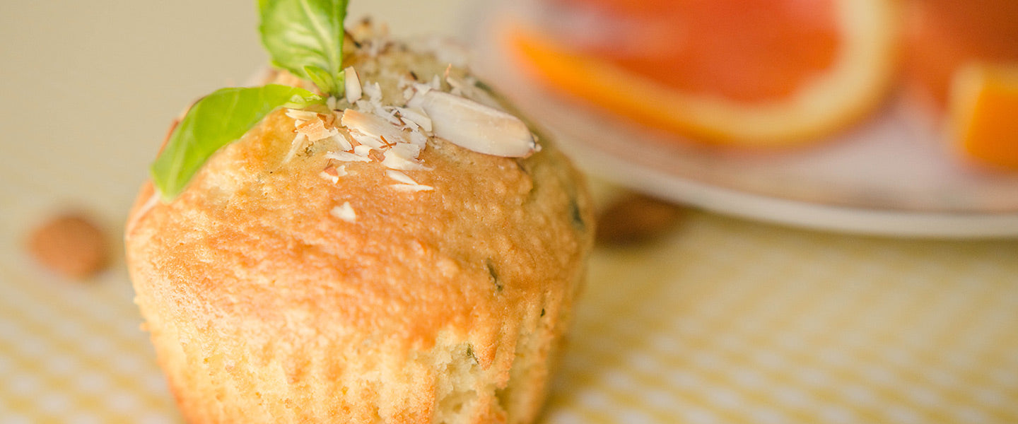 Orange and basil muffin topped with sliced almonds and fresh basil.