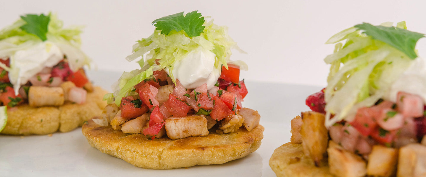 Turkey sopes topped with fresh tomato salsa, shredded lettuce, sour cream, and cilantro.
