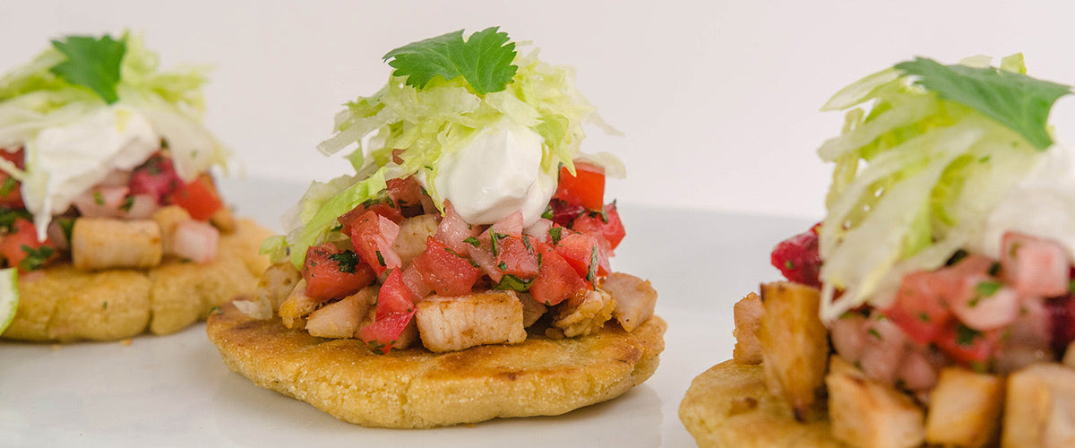 Turkey sopes topped with fresh tomato salsa, shredded lettuce, sour cream, and cilantro.