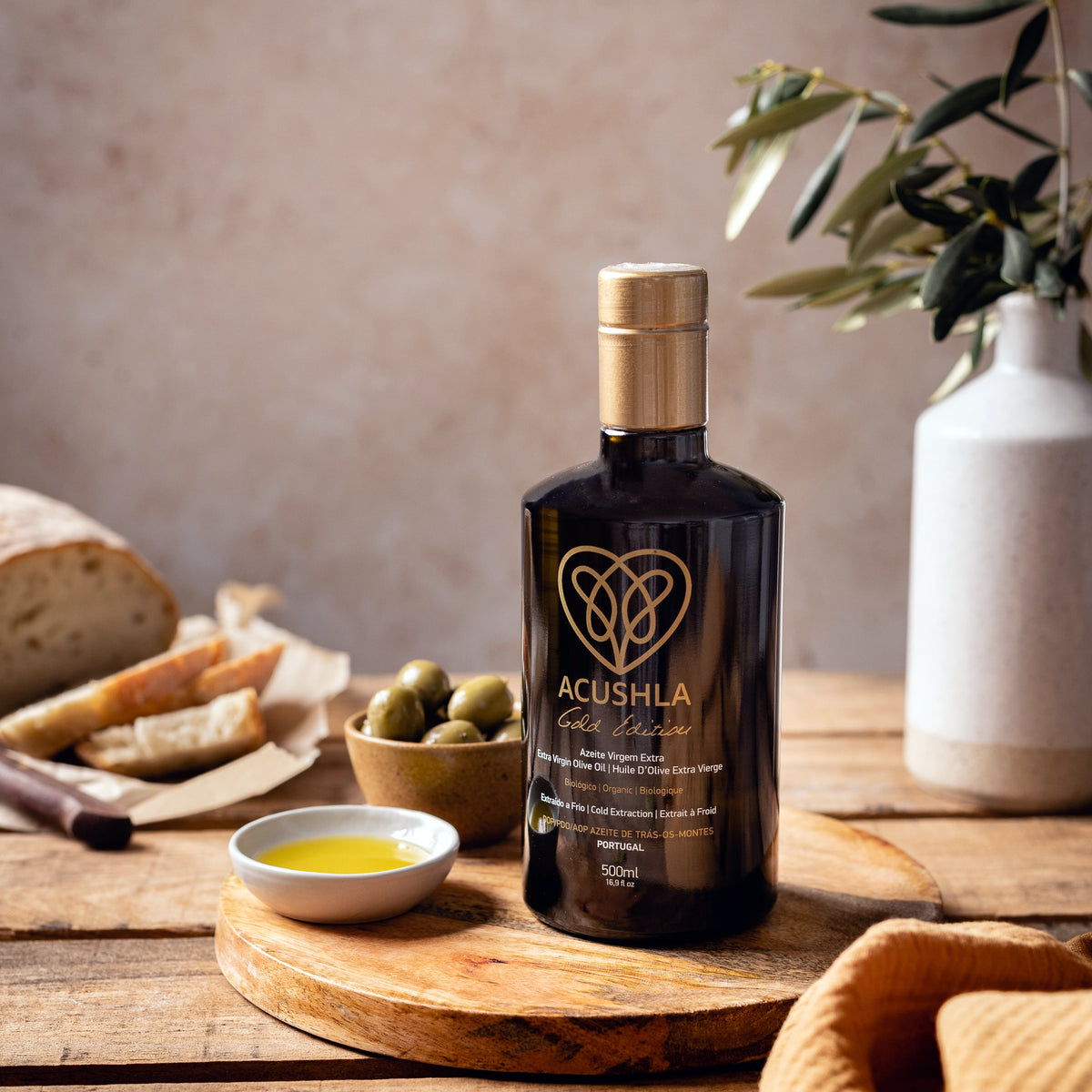 500 ml bottle of Acushla Gold Edition with a dish of olive oil, green olives, and bread.