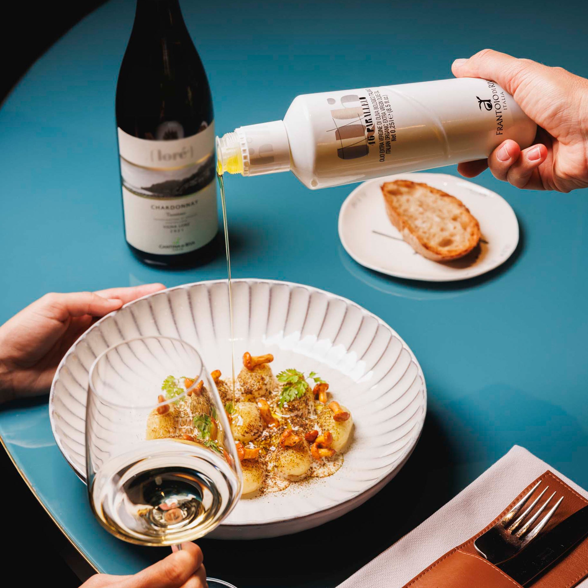46° Parallelo Organic 500 ml olive oil being poured over a plated dish at a restaurant table.