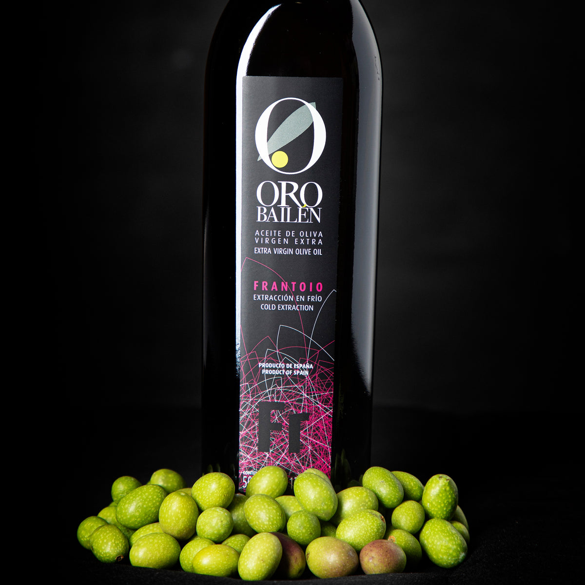 Oro Bailen Reserva Familiar Frantoio bottle standing behind fresh green olives.