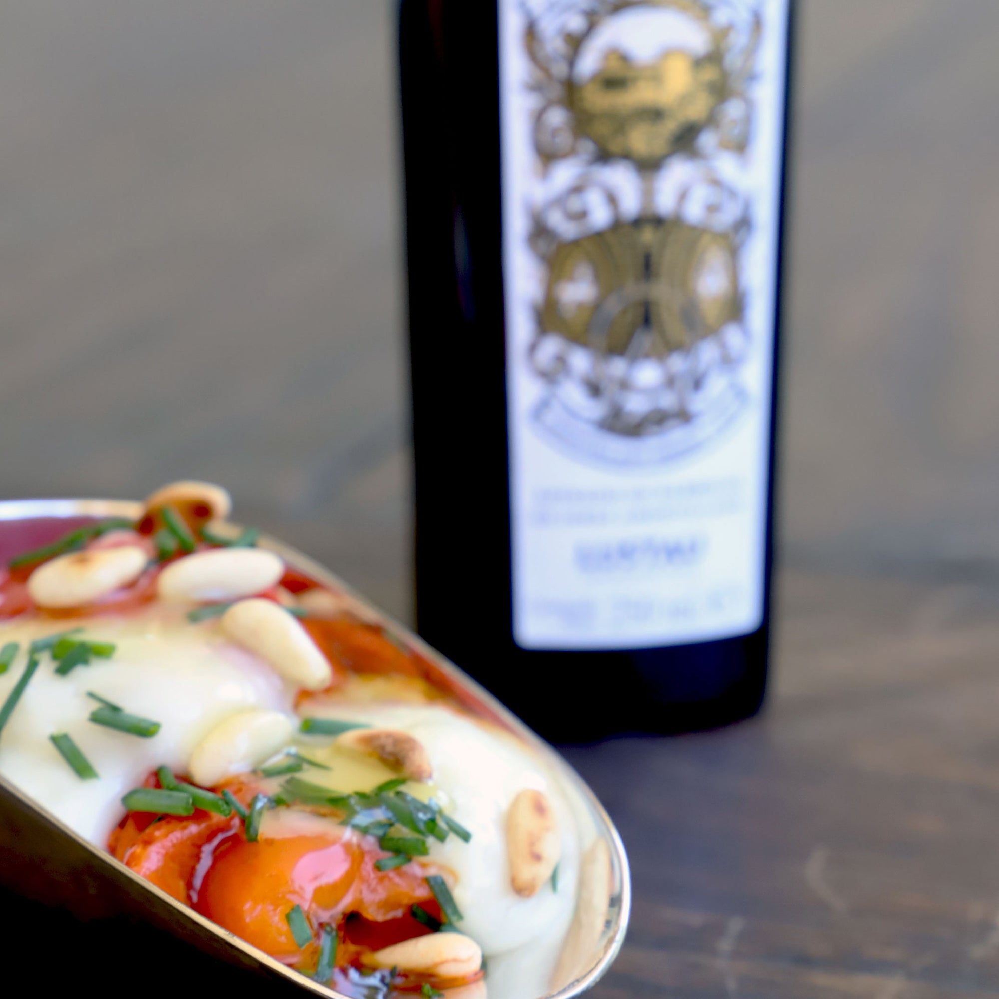 Egg dish topped with chives and nuts, with Arbequina Amontillado Sherry Cask bottle behind.