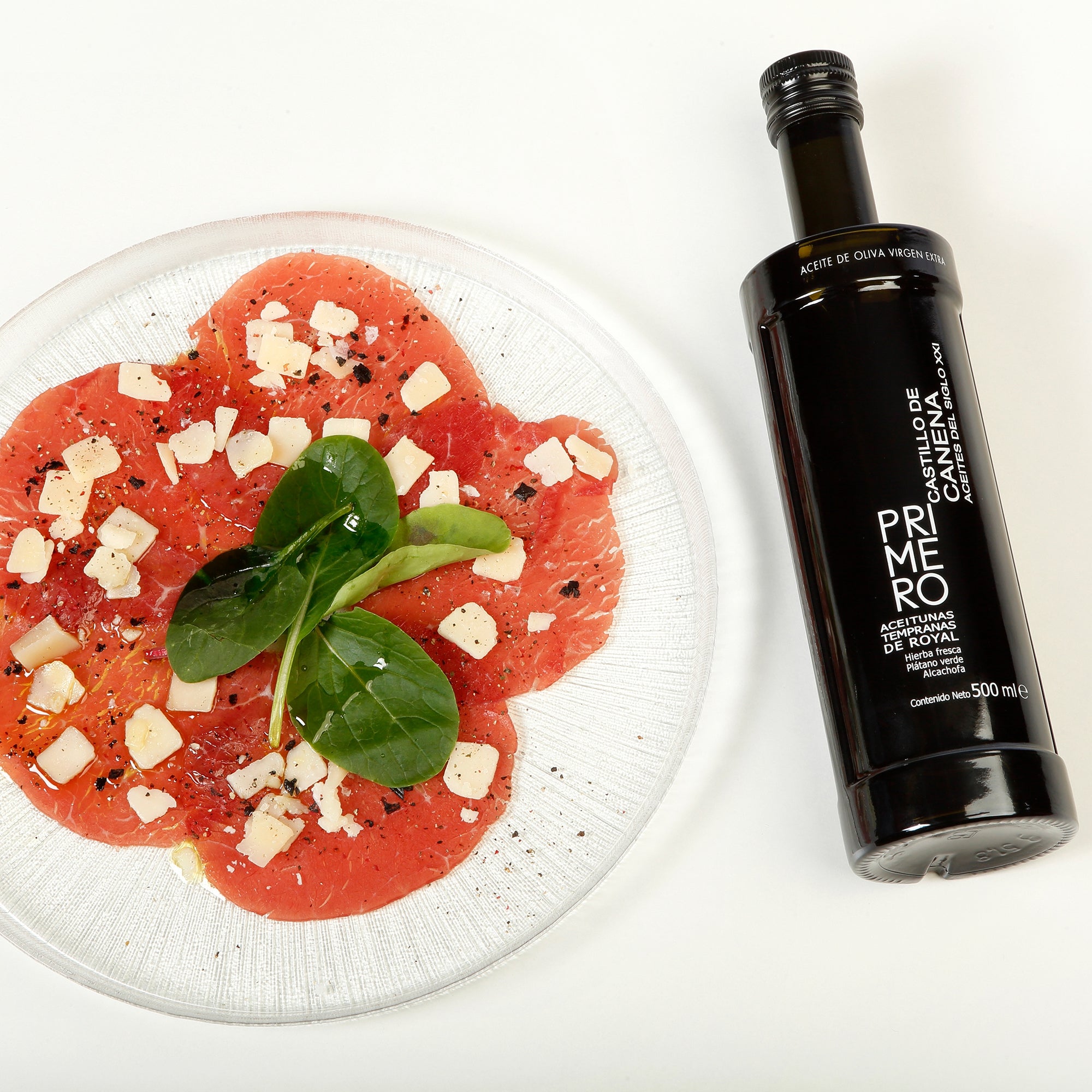Castillo de Canena Early Royal 500 ml bottle beside thinly sliced meat, cheese, greens, and seasoning.