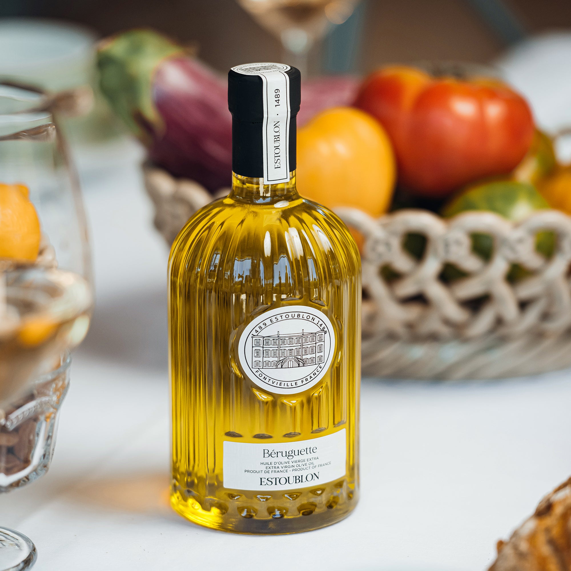 Estoublon Beruguette extra virgin olive oil bottle on a table with fresh vegetables.