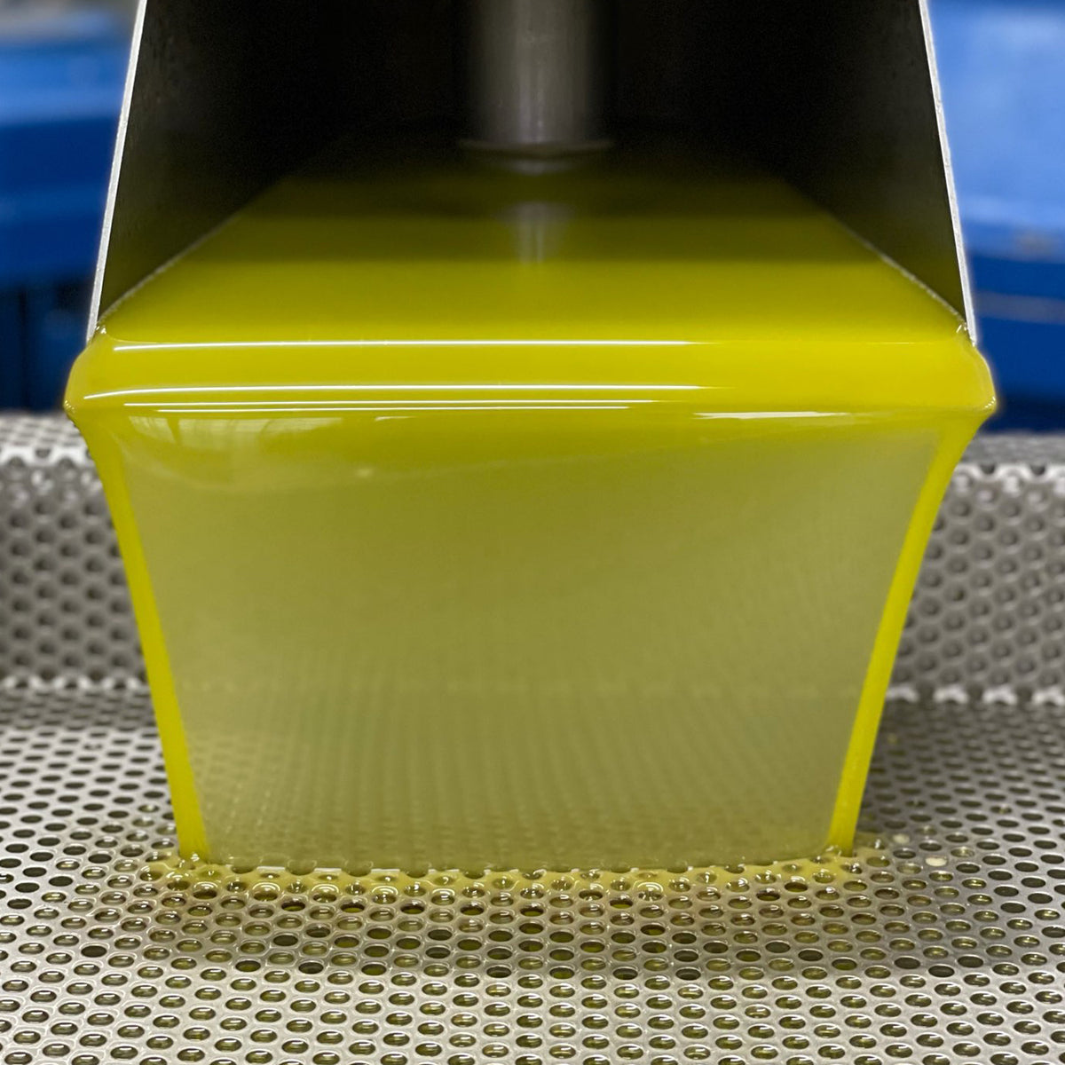 Fresh olive oil flowing from a stainless-steel mill.