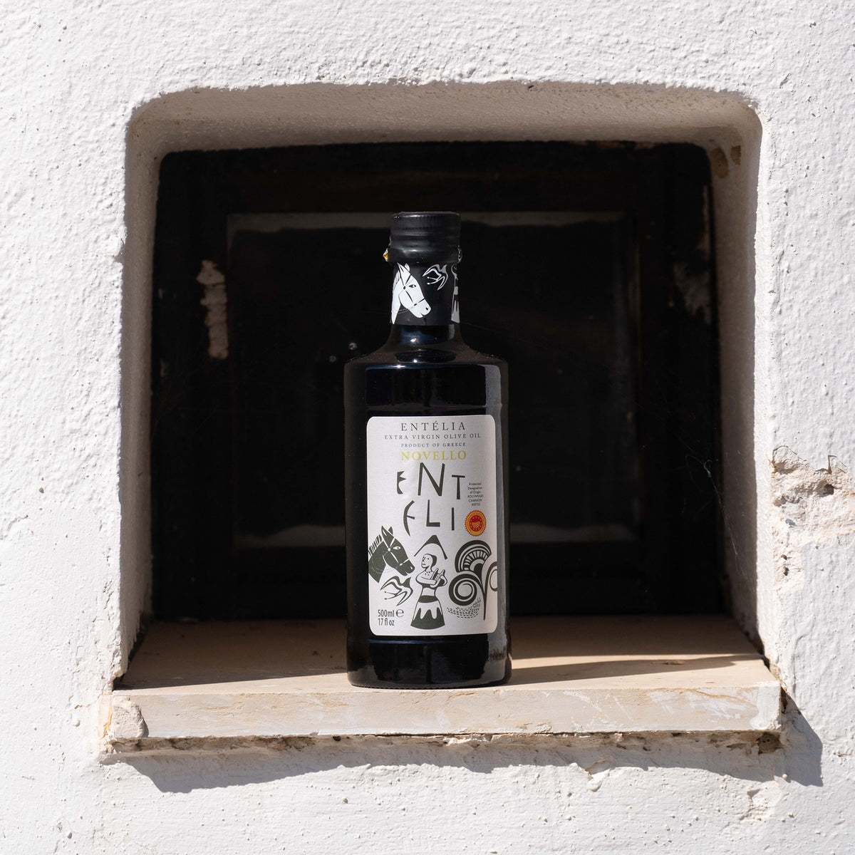 Entelia Novello 500ml olive oil bottle inside a rustic wall niche.