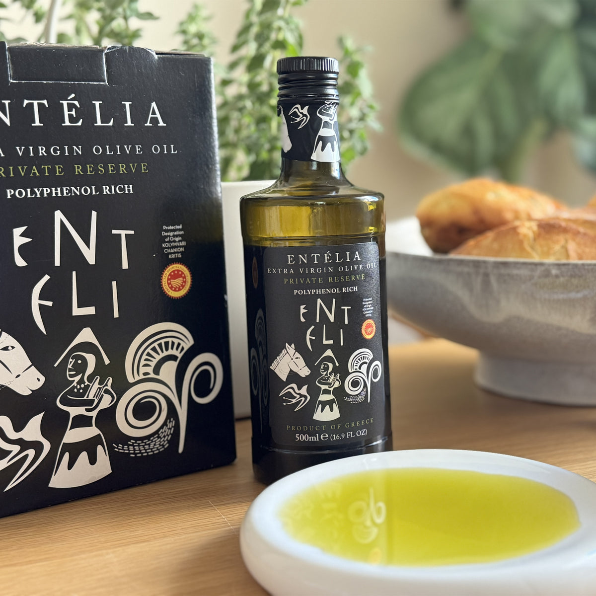 A 3L Bag-In-Box and a 500ml bottle of Entelia Private Reserve beside olive oil dish and bread.