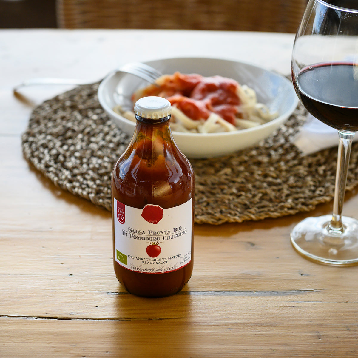Pasta topped with Frantoi Cutrera Organic Cherry Tomato Ready Sauce, and a glass of red wine.