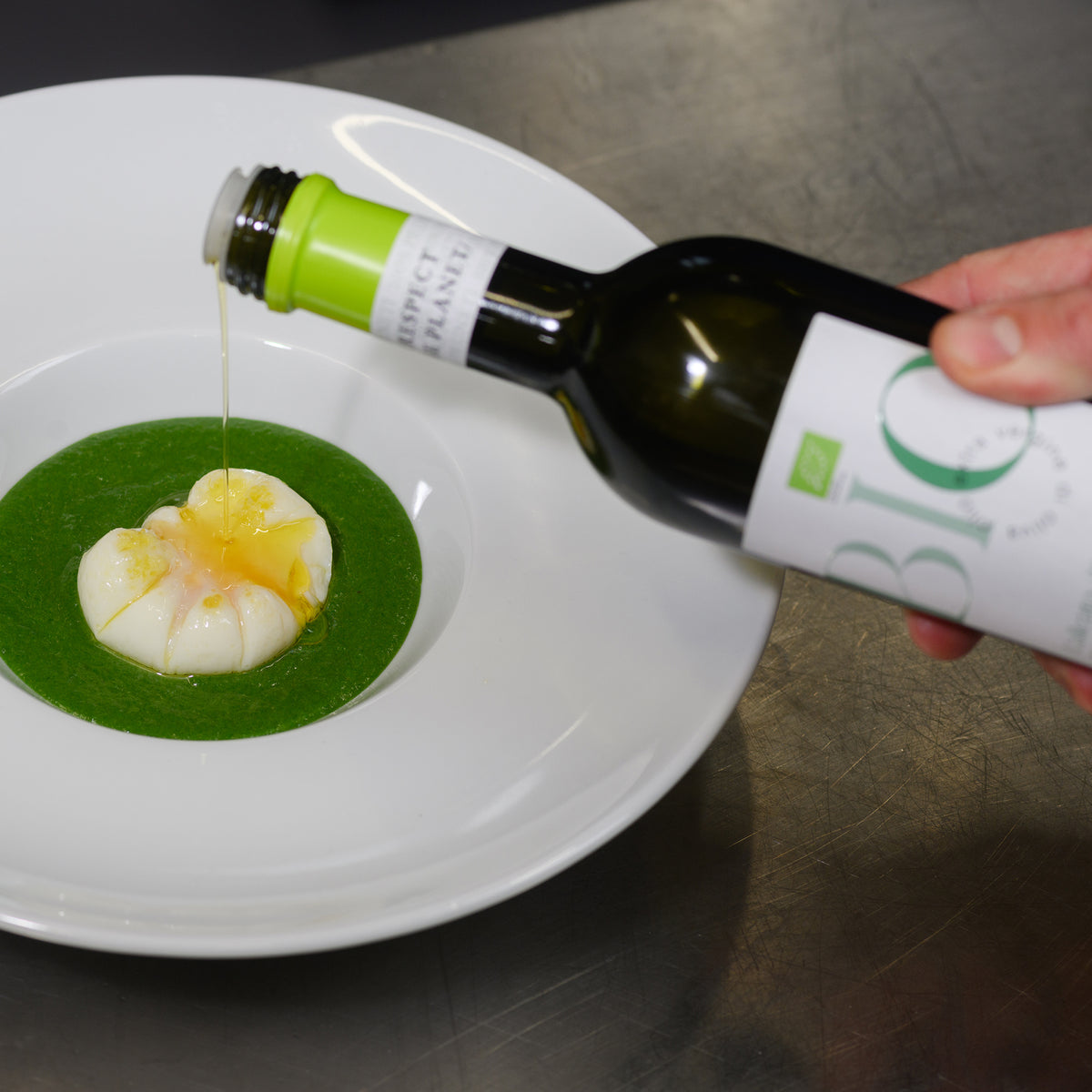 Pruneti L'Alleato Organic 750ML olive oil being poured over a plated dish with sauce.