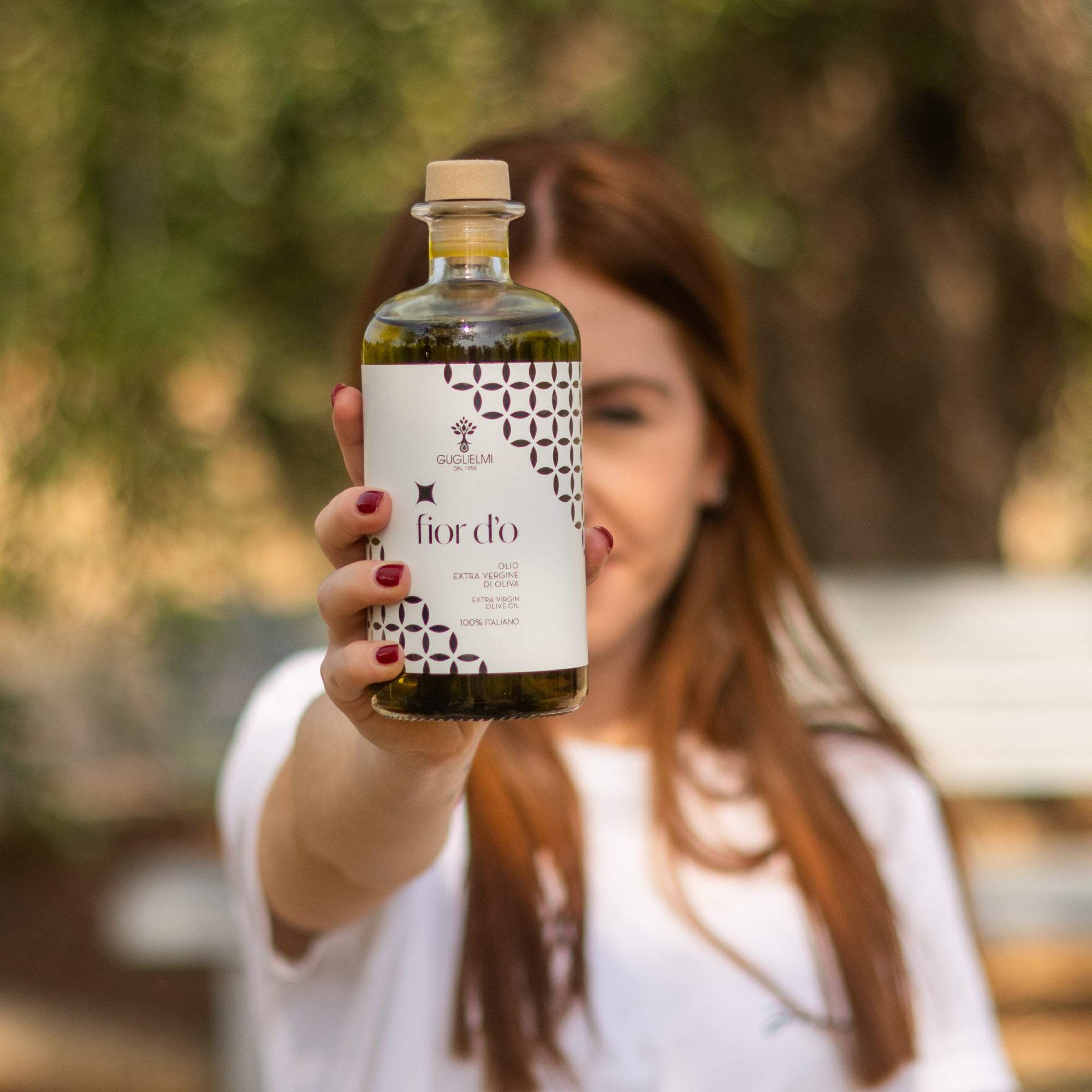 A woman holding a Guglielmi Fior D'O Nuovo 500ml bottle.