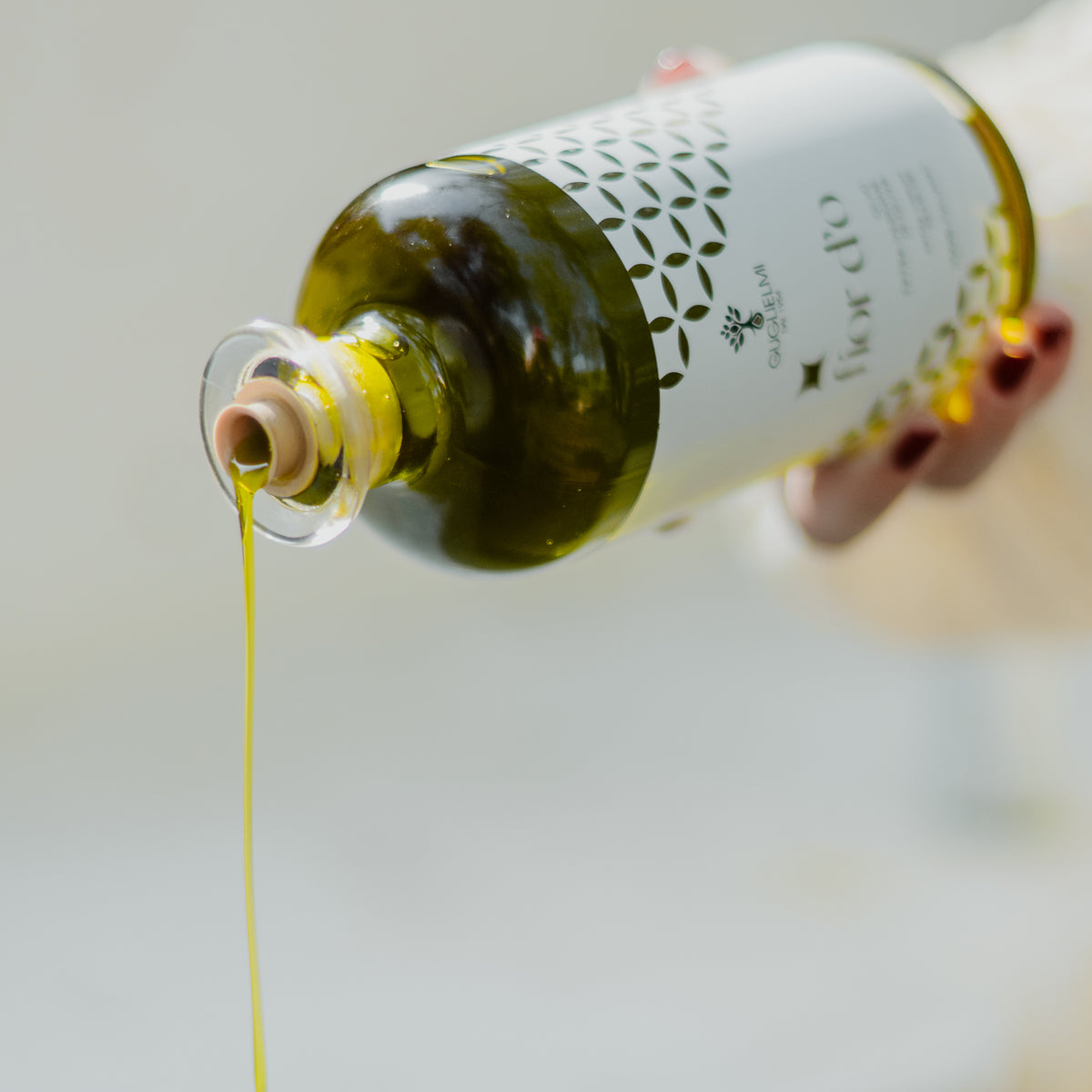 Pouring olive oil from a Guglielmi Fior D'O Nuovo 500ml bottle.