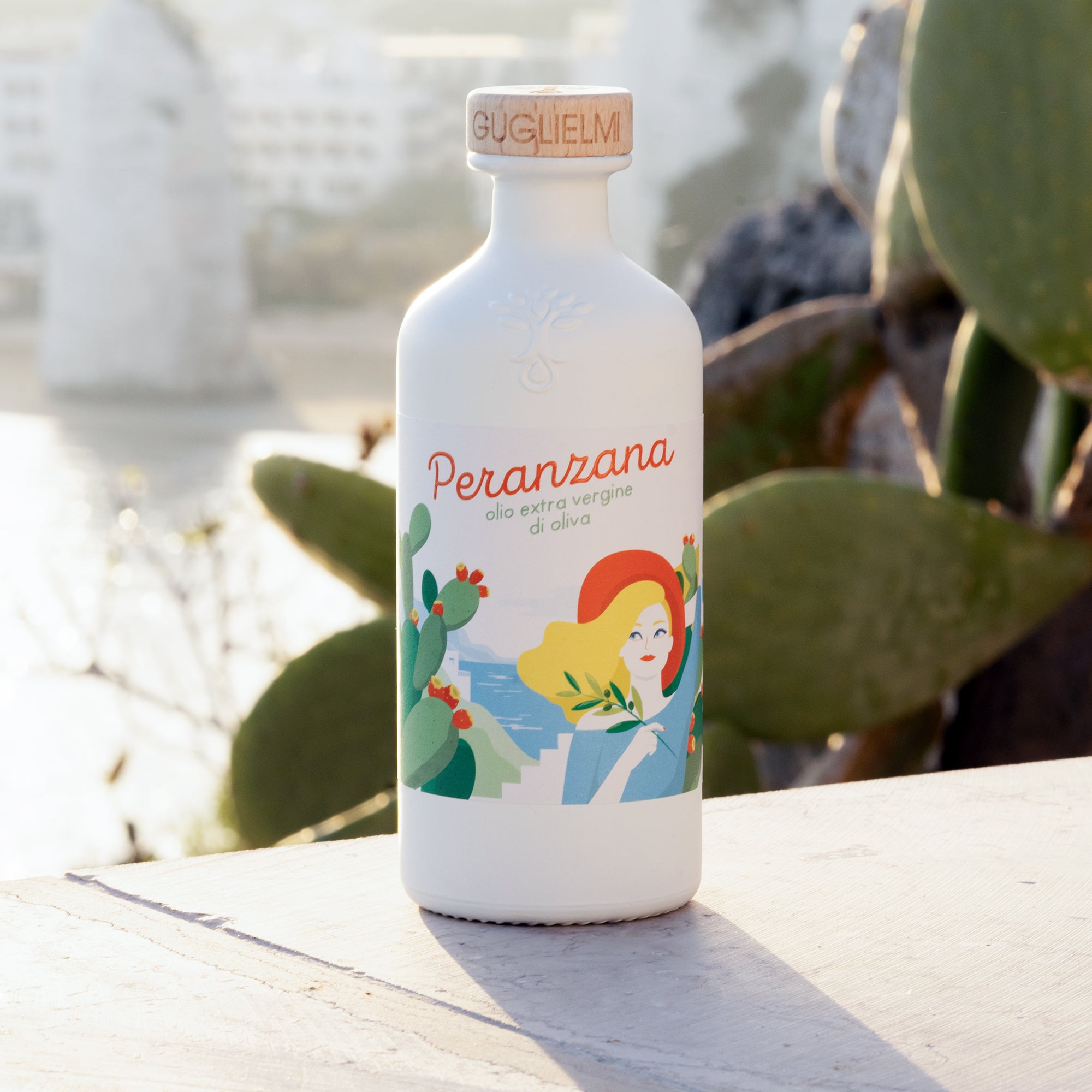 500 ml Guglielmi Peranzana extra virgin olive oil bottle beside prickly pear cactus in bright sunlight.