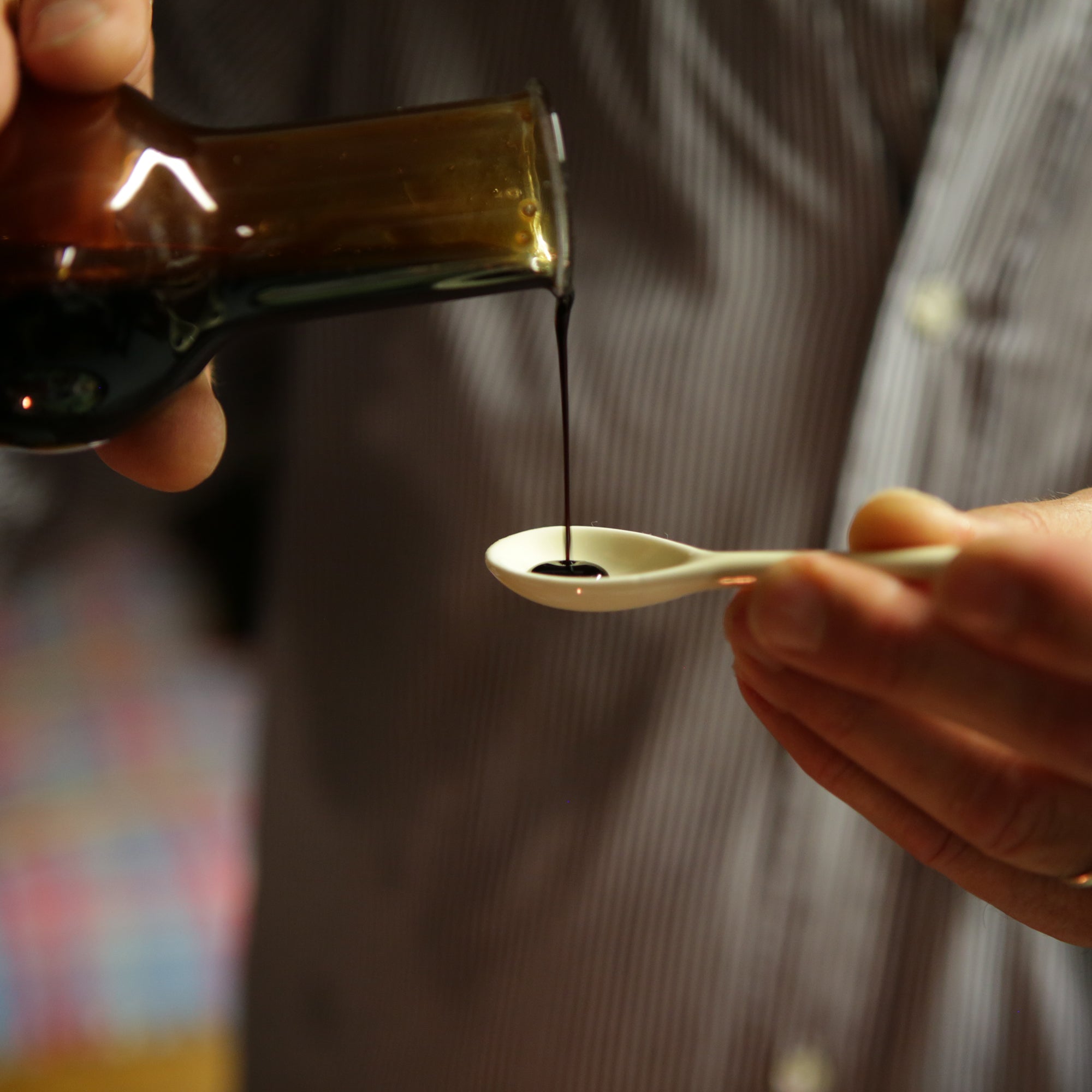 Mussini balsamic vinegar being poured from a tasting glass onto a spoon.