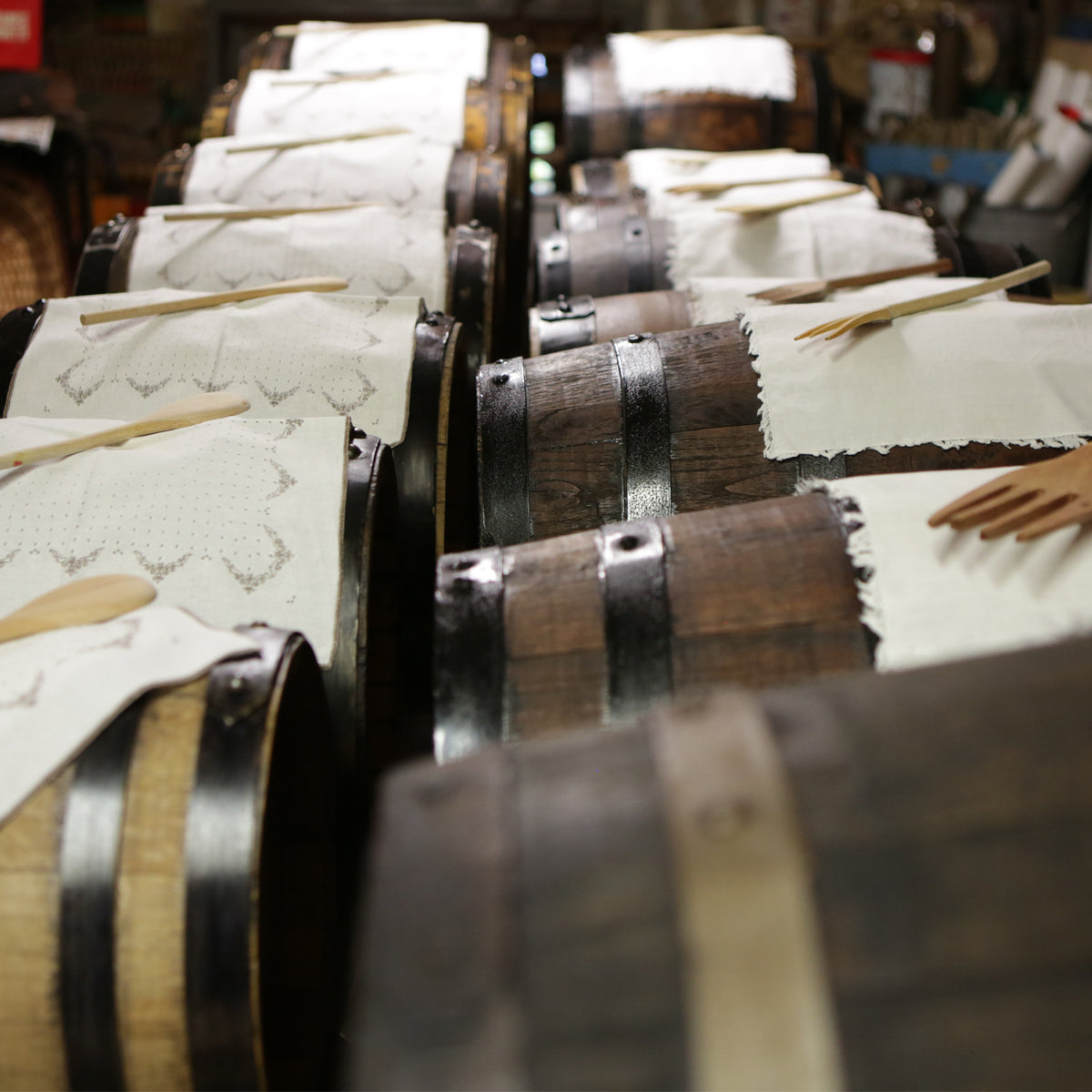 Rows of Mussini wooden vinegar barrels covered with tasting cloths and wooden spoons.