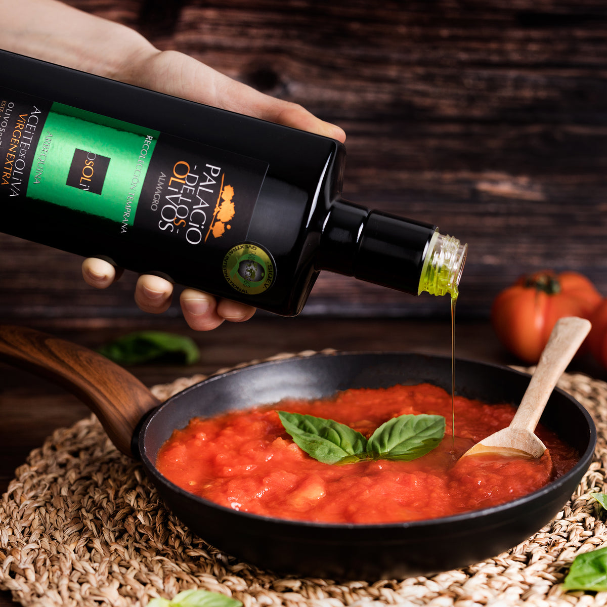 Palacio de los Olivos Arbequina olive oil poured into a pan of tomato sauce with basil.