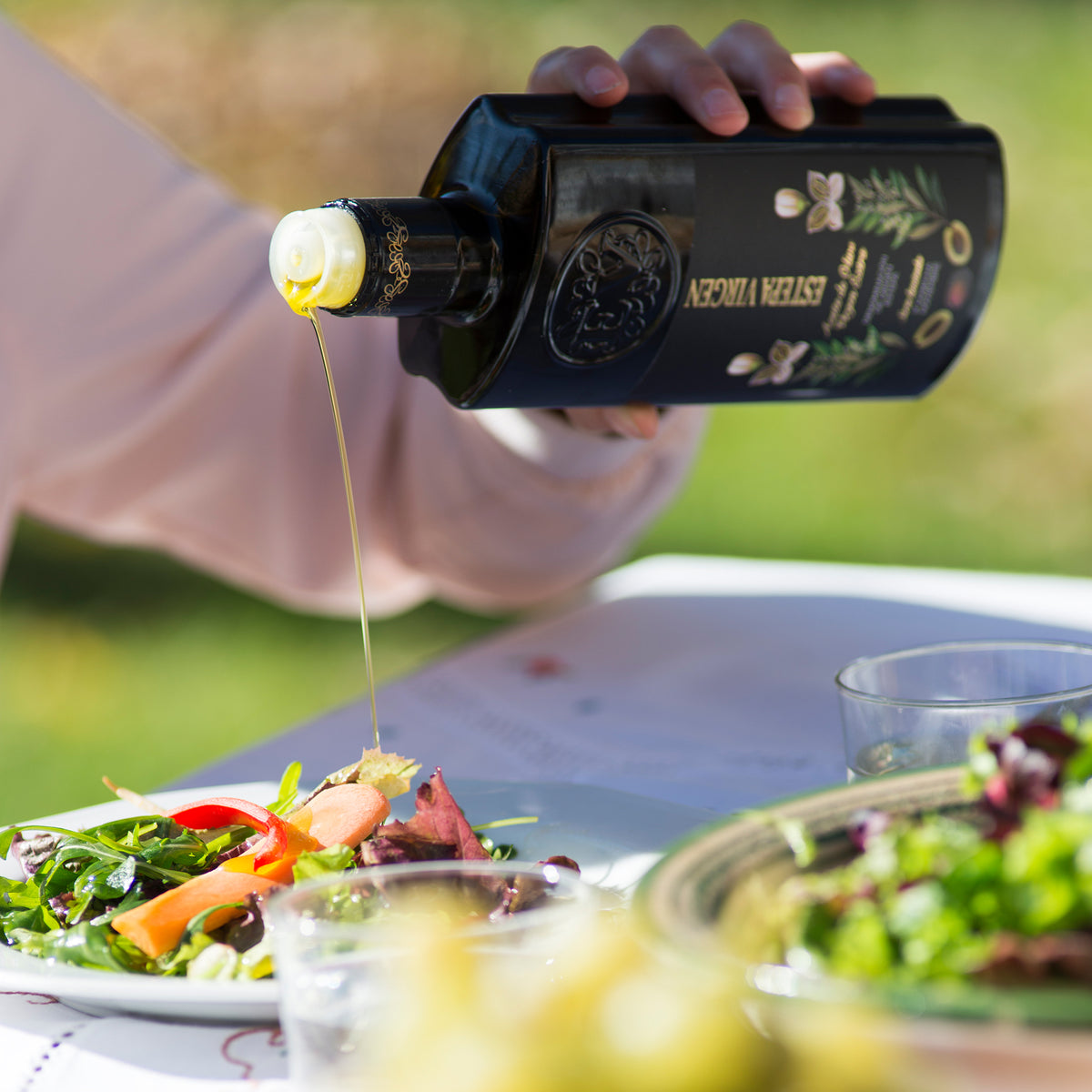 Pouring premium Estepa Virgen extra virgin olive oil over garden vegetables.
