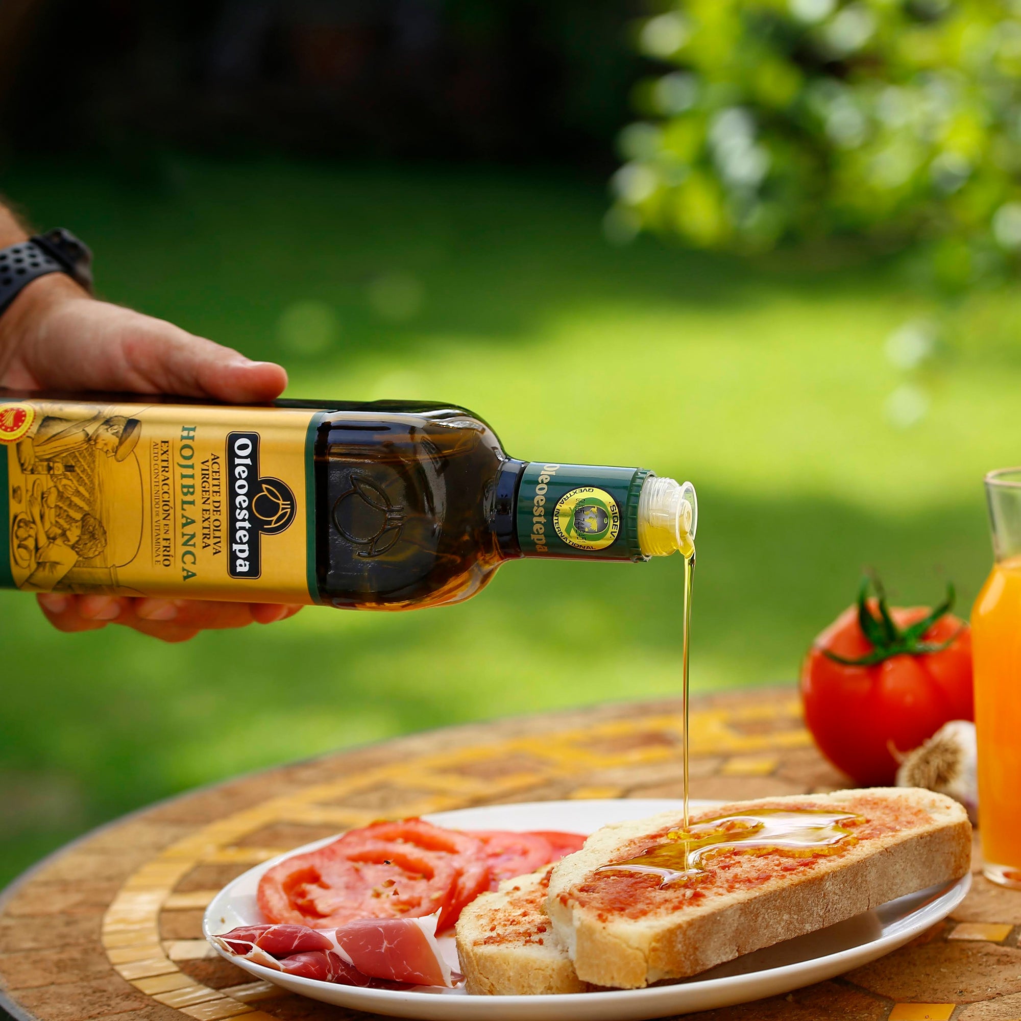Oleoestepa Hojiblanca olive oil poured over bread, served with sliced tomatoes and cured ham.