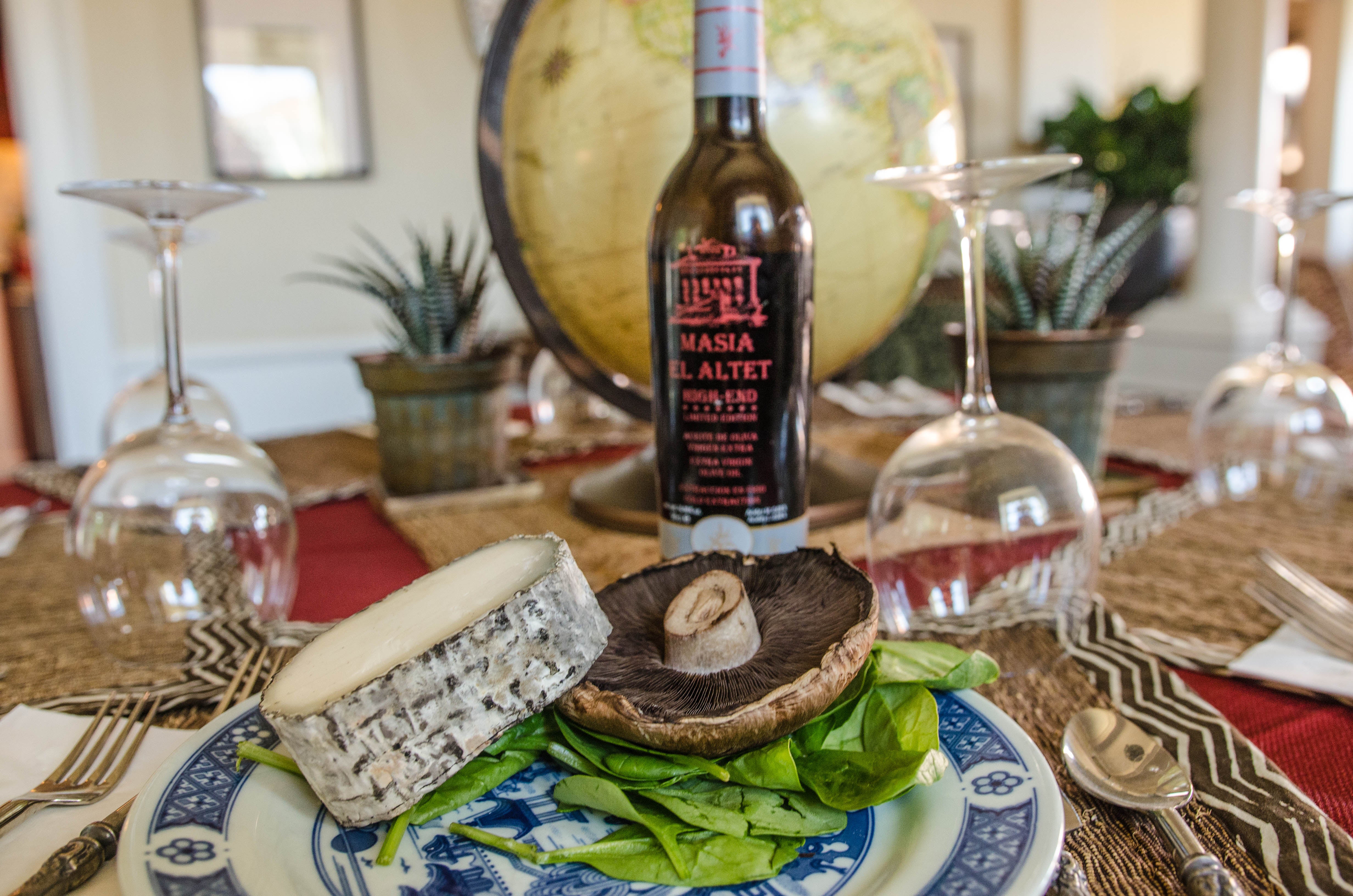 A bottle of Masia el Altet High End on a table, next to a fresh mushroom.