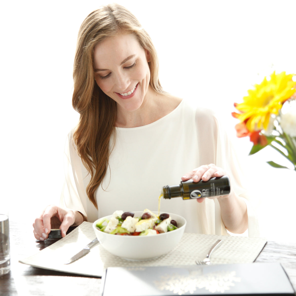 Joanne Lacina pours olive oil from the tasting kit over a fresh salad.