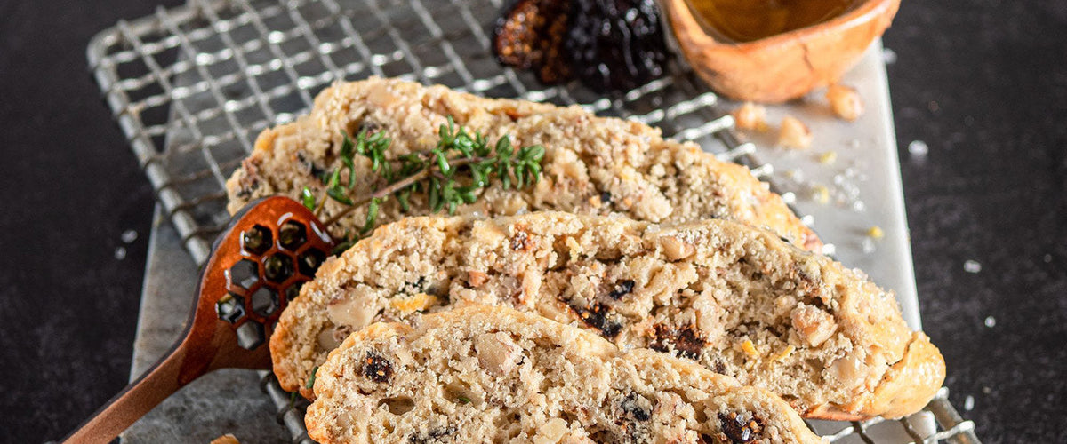 Sliced walnut and dried fig biscotti garnished with fresh thyme.
