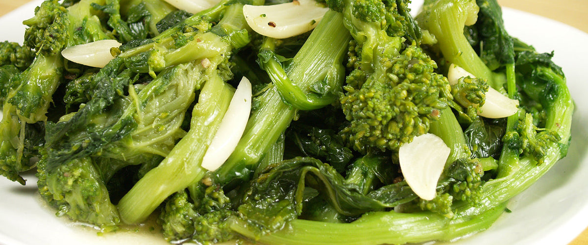 Broccoli rabe with tender stems, leafy greens, sliced garlic, olive oil, and seasonings.