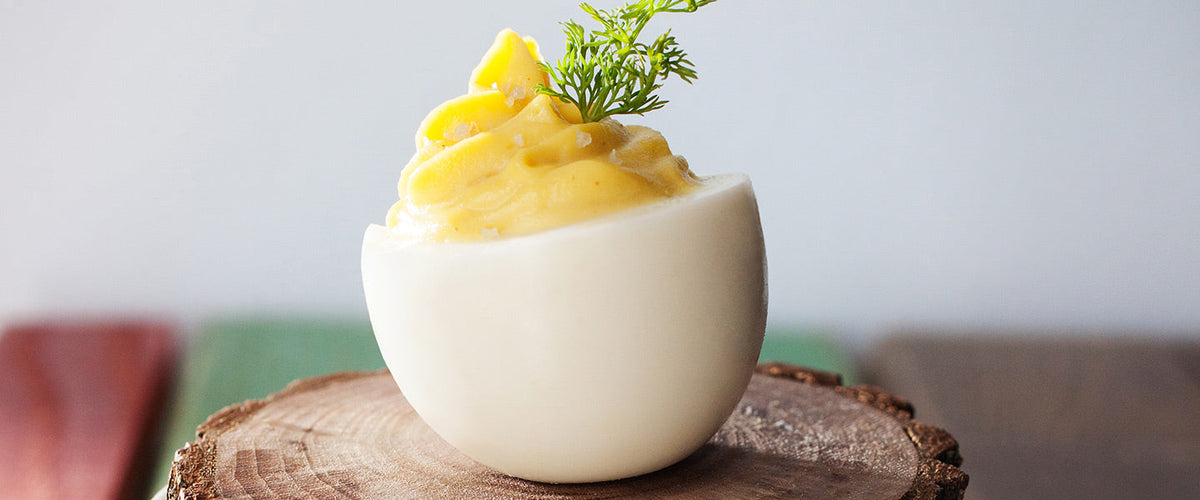 A deviled egg filled with creamy whipped yolk and garnished with fresh dill.
