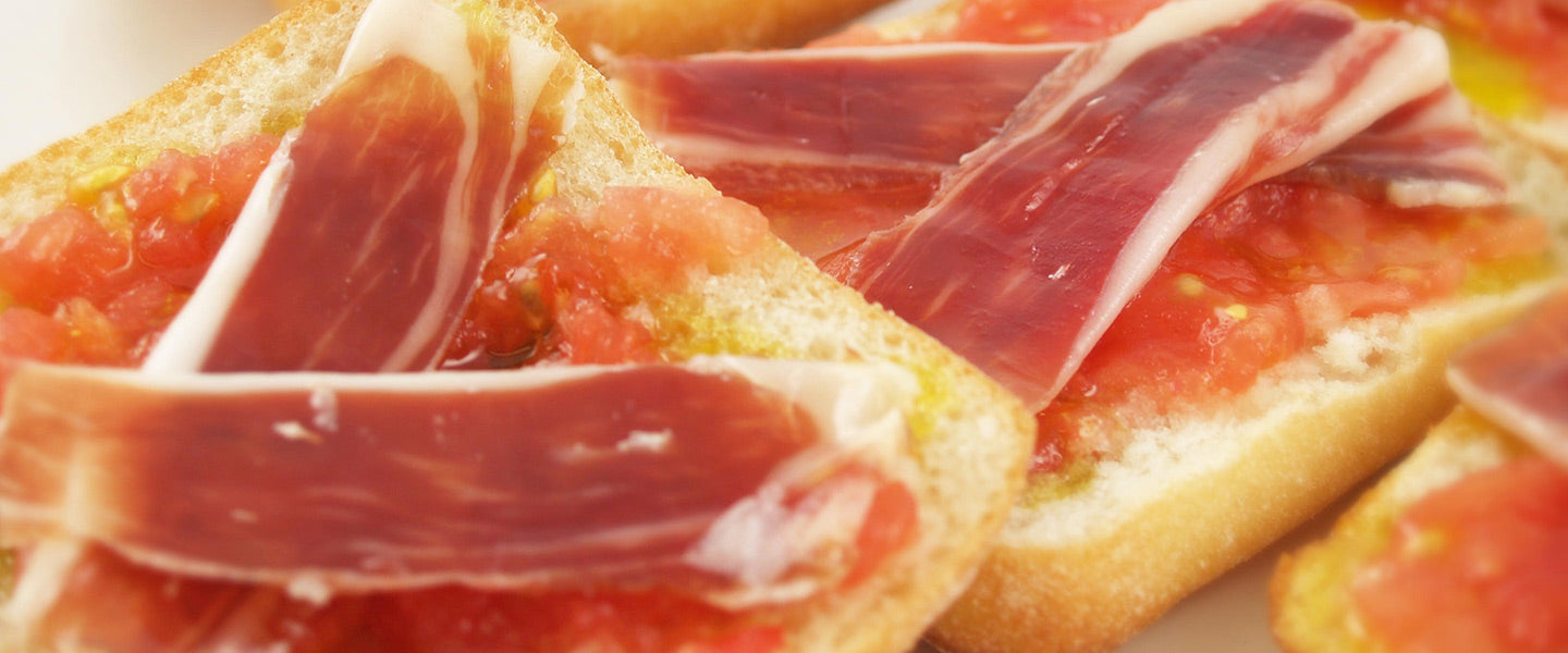 Pan tumaca — crusty bread spread with ripe tomato and olive oil, topped with slices of cured ham.