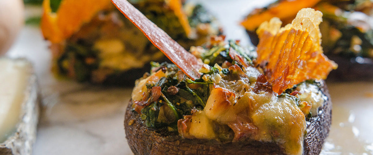 Baked portobello mushroom filled with melted cheese, spinach, herbs, and prosciutto.