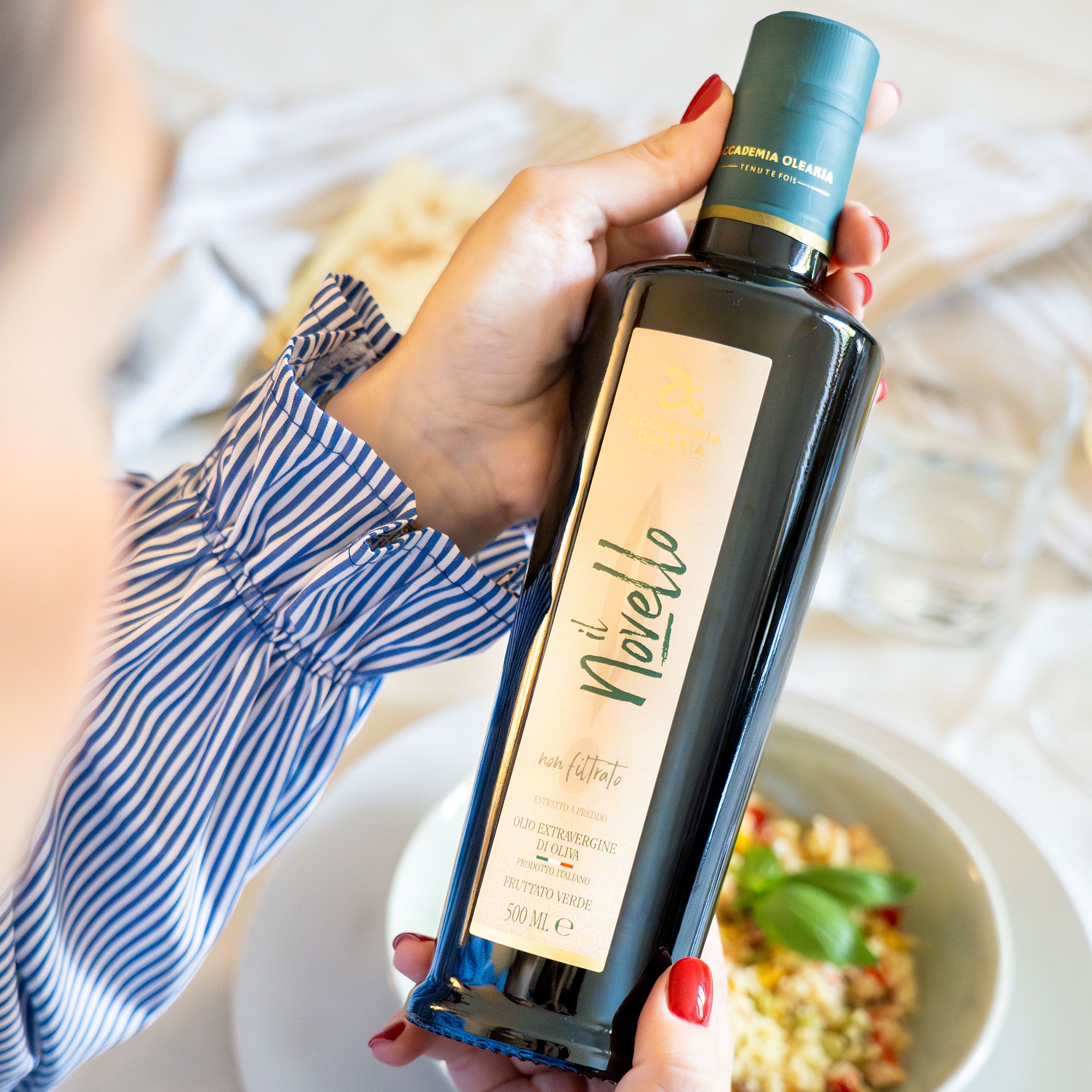 A 500 ml Accademia Olearia il Novello bottle beside a bowl of food.