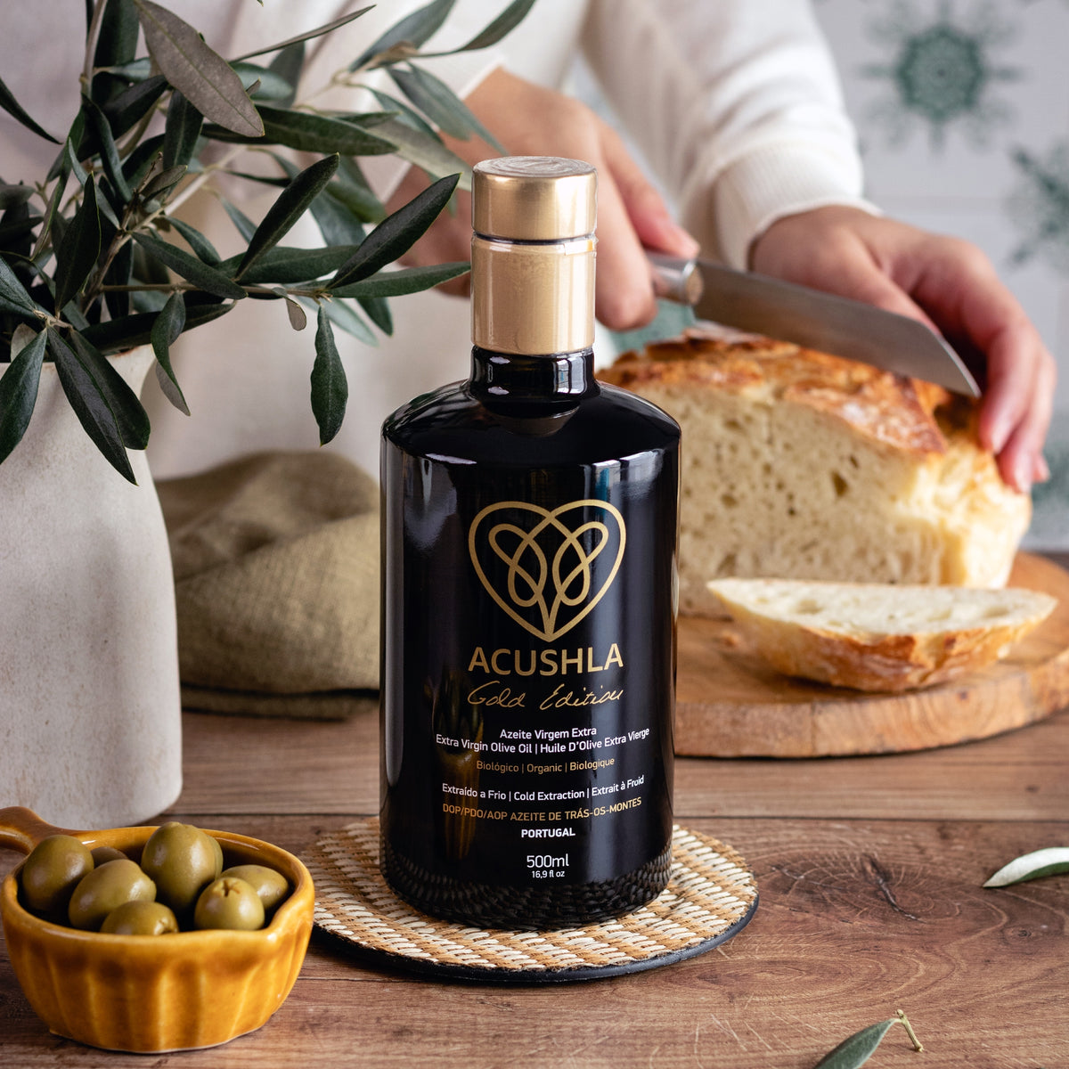 Acushla Gold Edition 500 ml bottle beside green olives and freshly sliced bread.