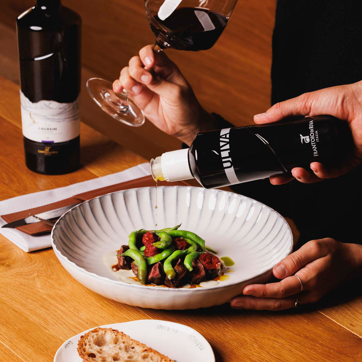 Uliva extra virgin olive oil poured over a plated dish with green beans and meat.
