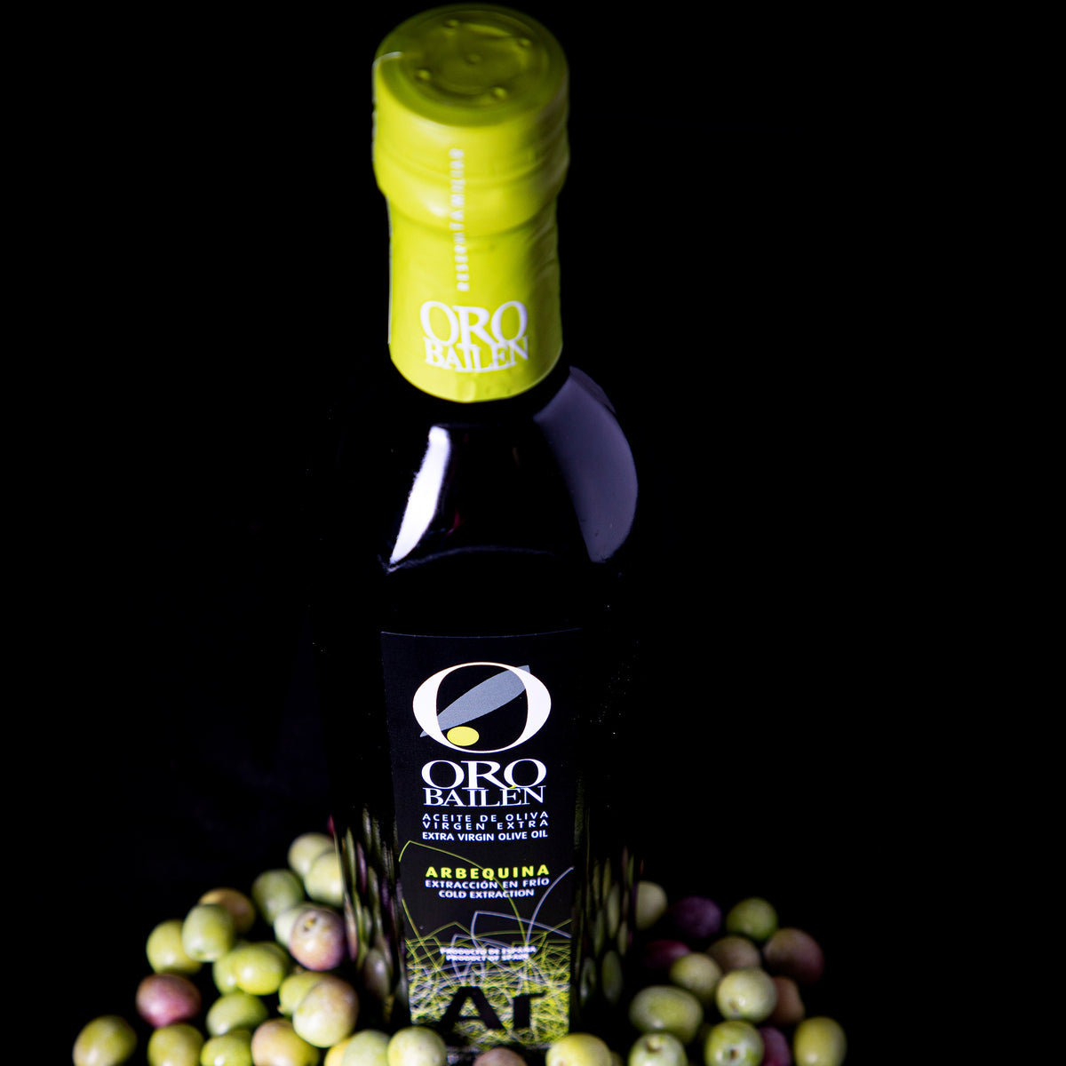 Oro Bailen Reserva Familiar Arbequina among freshly harvested green and purple olives.