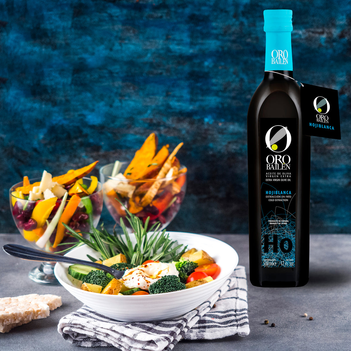 Oro Bailen Hojiblanca 500 ml bottle beside bowls of colorful vegetables and salad.