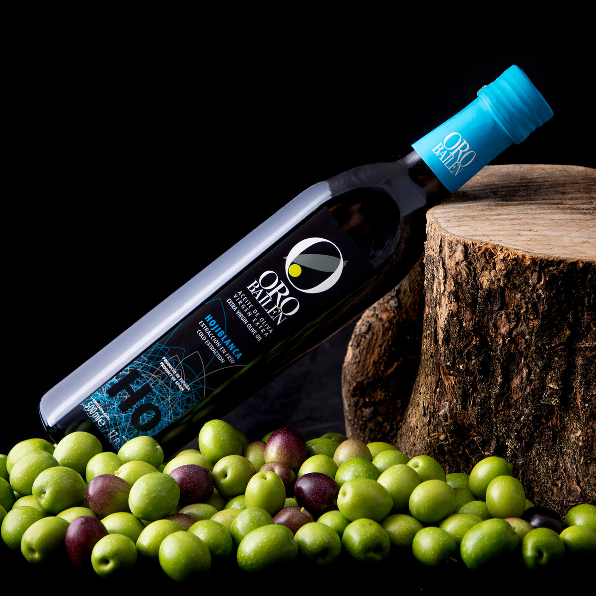 Oro Bailen Hojiblanca 500 ml bottle, surrounded by fresh green and purple olives.