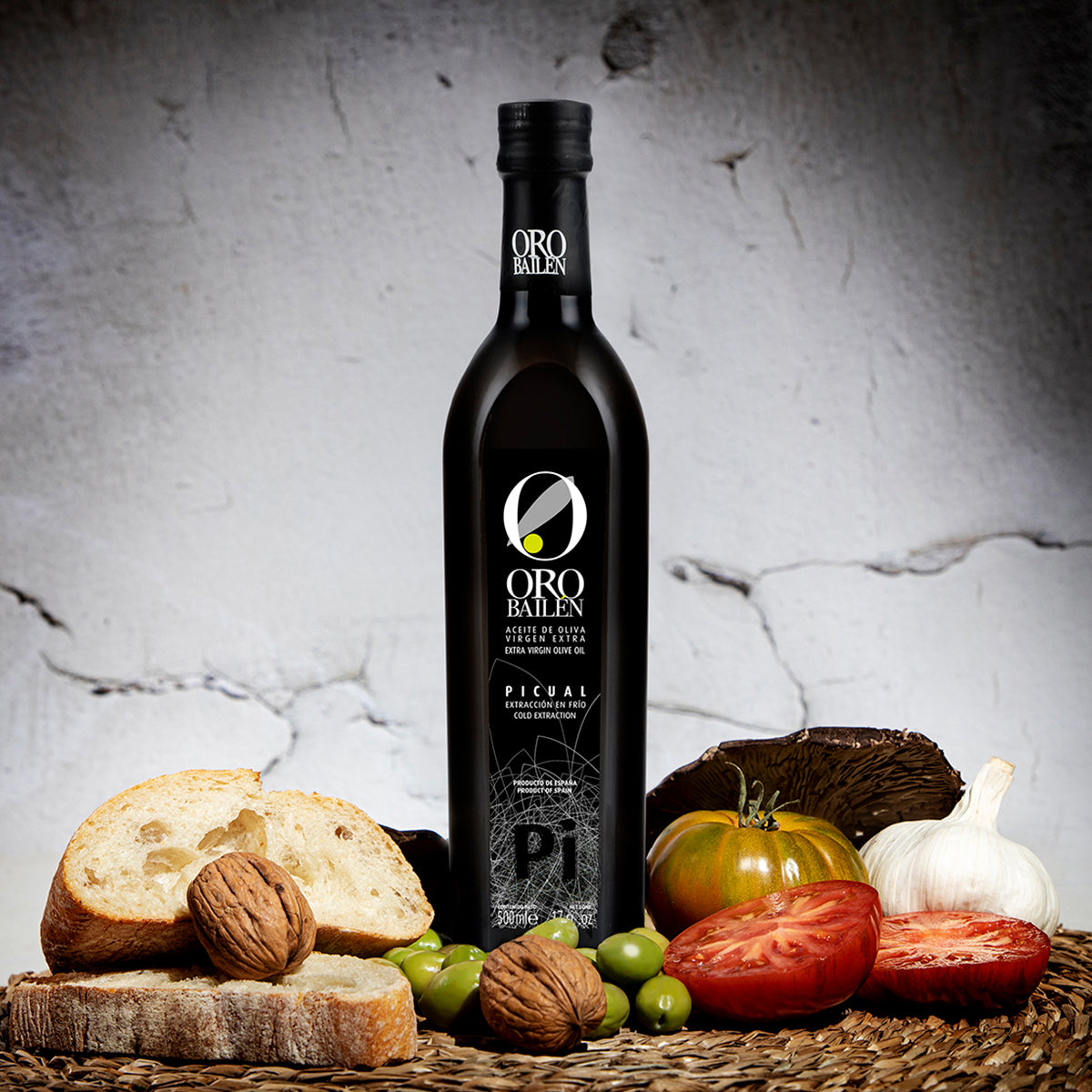 Oro Bailen Reserva Familiar Picual 500ml bottle with bread, tomatoes, olives, walnuts, and garlic.