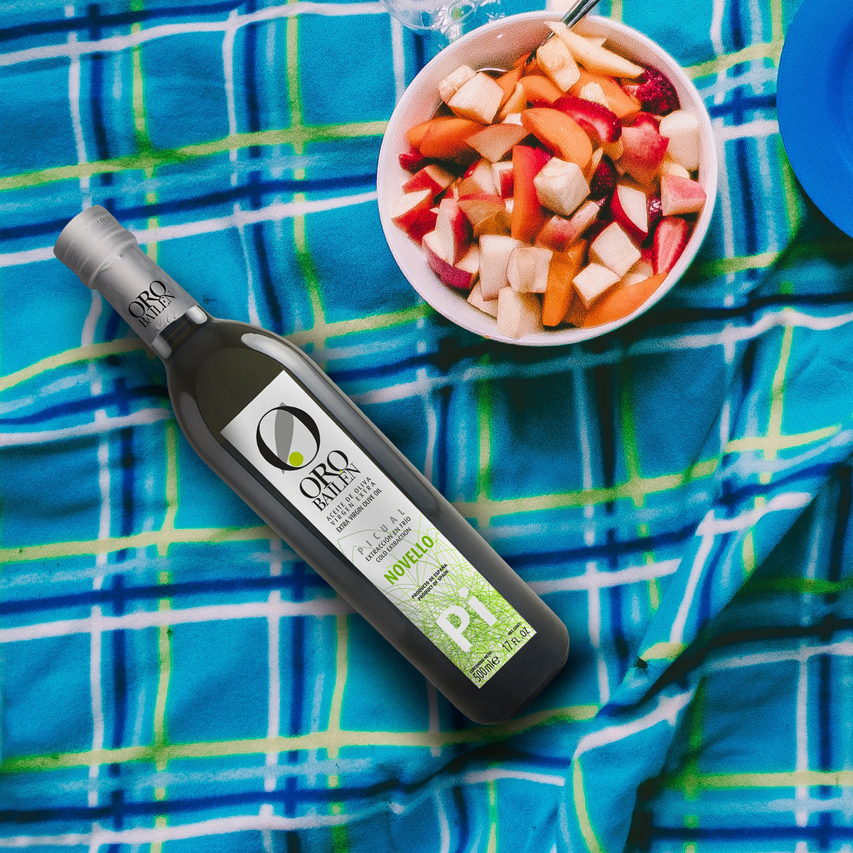 A 500ml bottle of Oro Bailen Picual Novello beside a fruit salad.