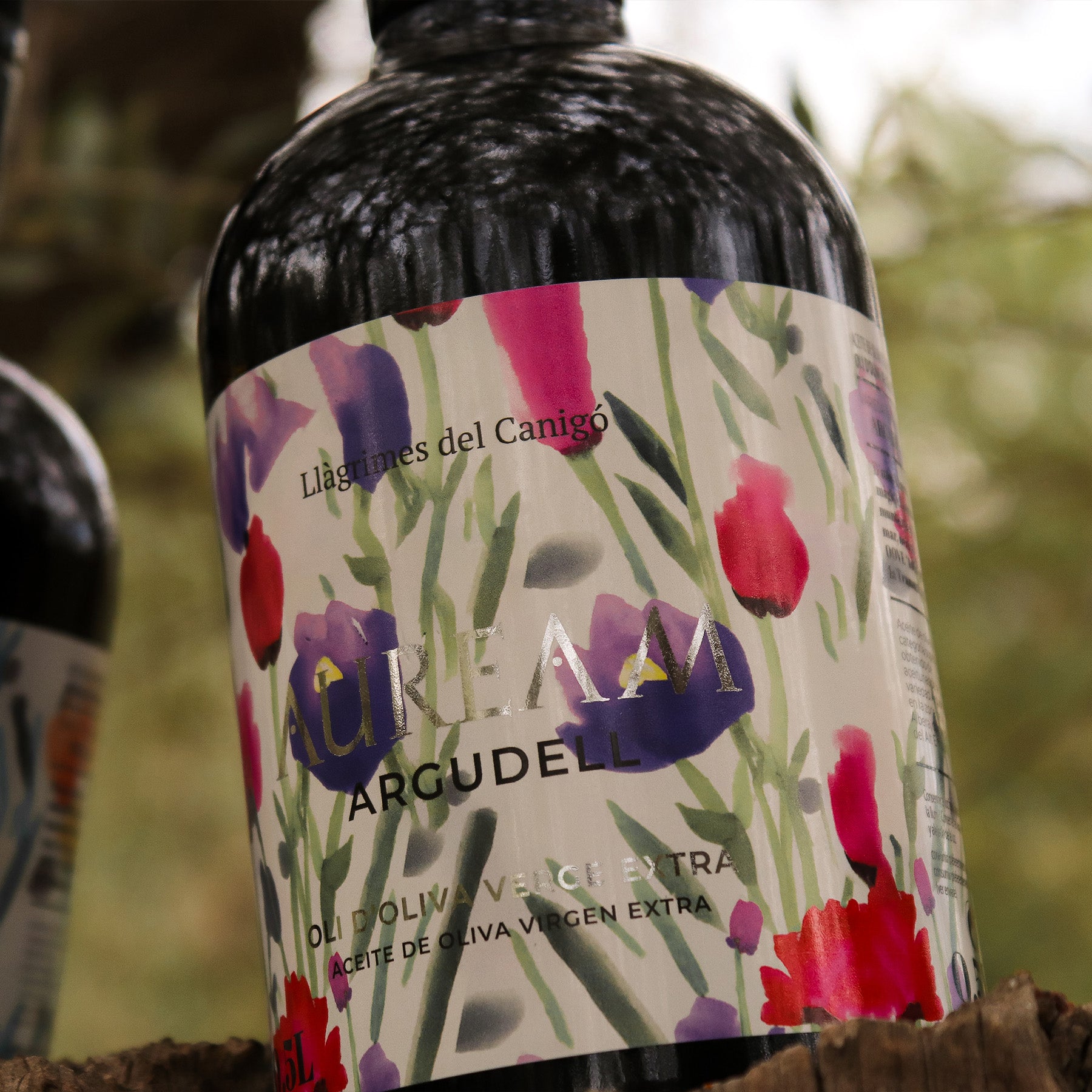 Close-up of the Auream Argudell 500 ml bottle among olive trees.