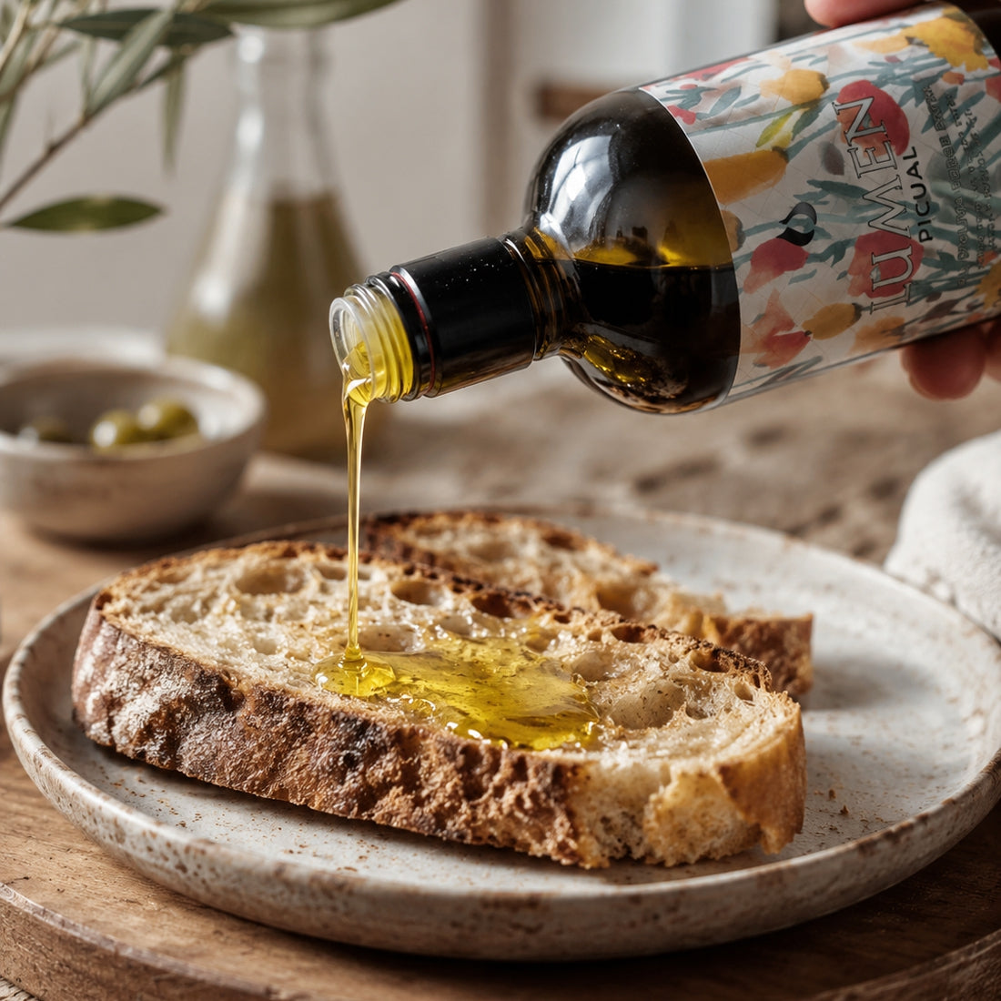 Llàgrimes del Canigó Lumen Picual olive oil pouring onto rustic bread.