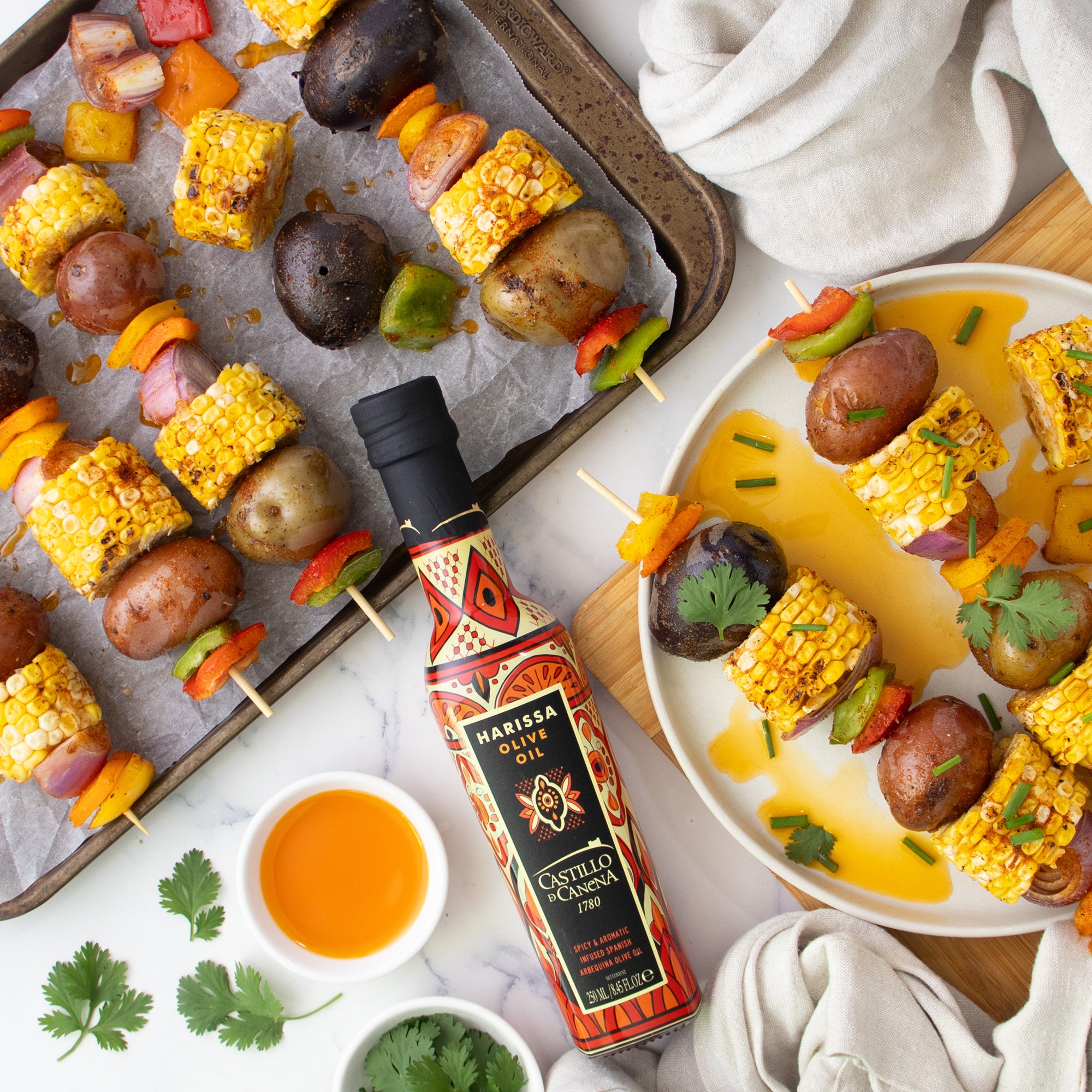 Castillo de Canena Harissa Arbequina 250ML with grilled corn, potatoes, peppers, herbs, and vegetable skewers.