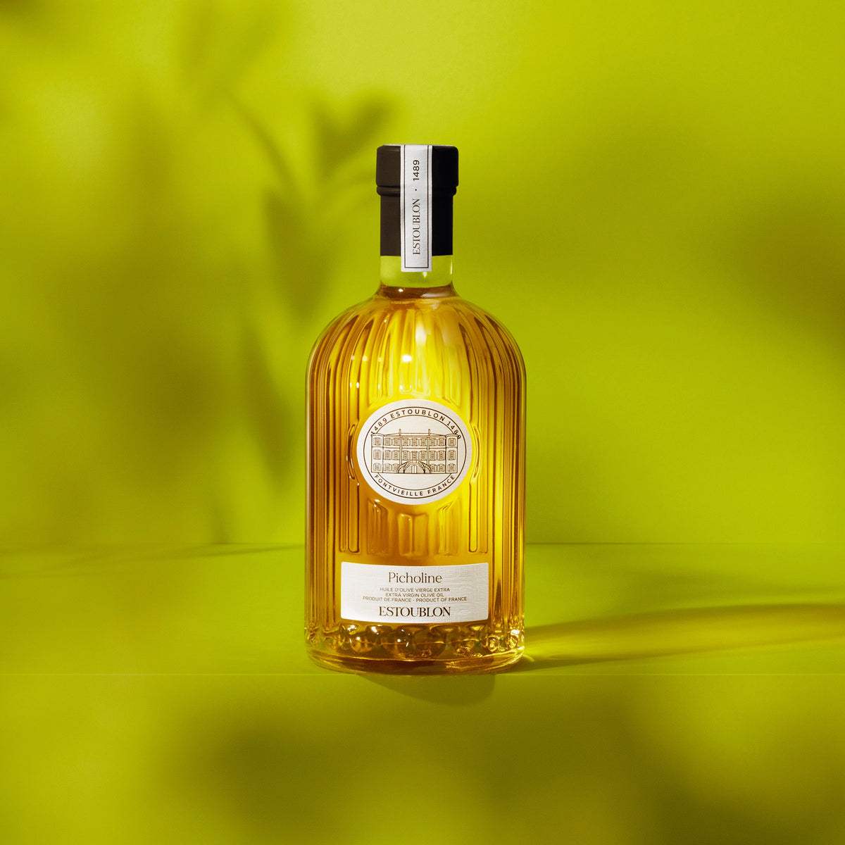 Estoublon Picholine 500 ml Frence olive oil bottle against a vivid green background.