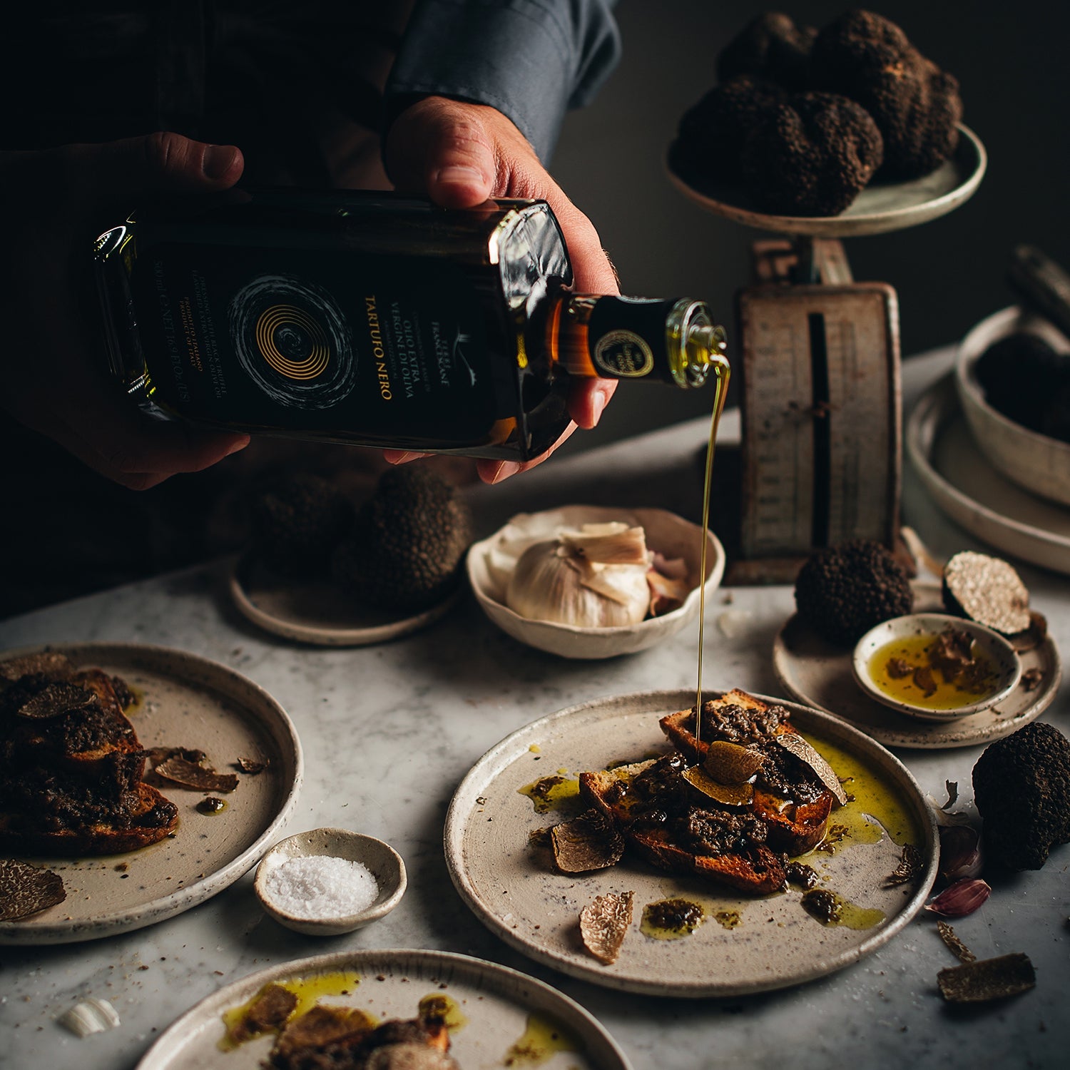 Terre Francescane Black Truffle olive oil being poured over bread topped with black truffle shavings.