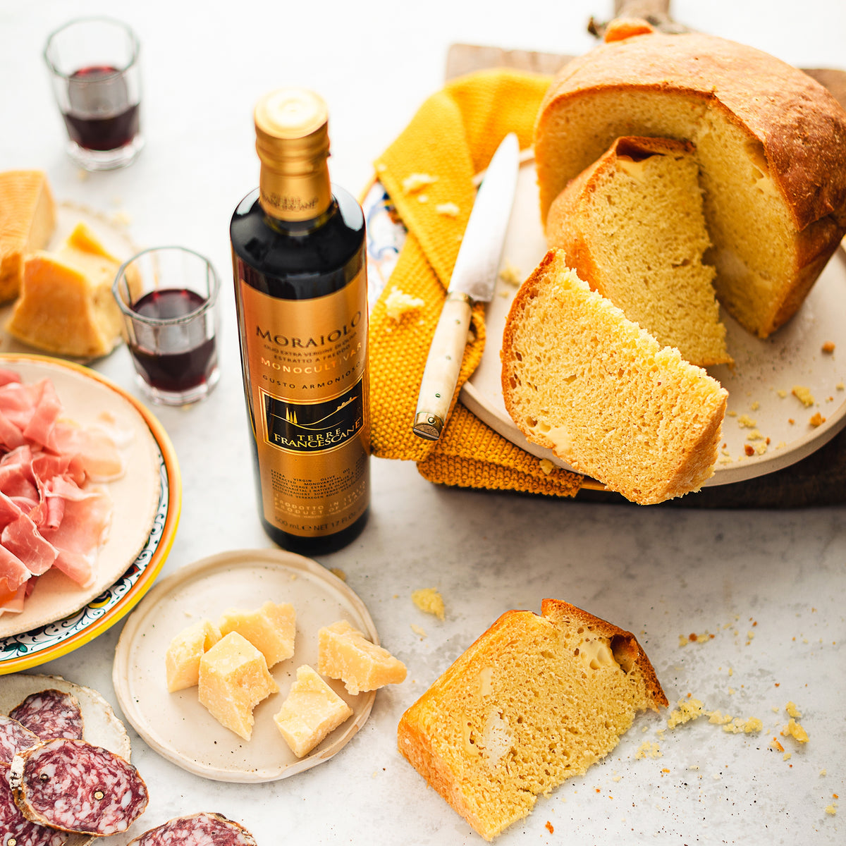 Terre Francescane Moraiolo 500 ml bottle beside sliced bread, cheeses, cured meats, and red wine.