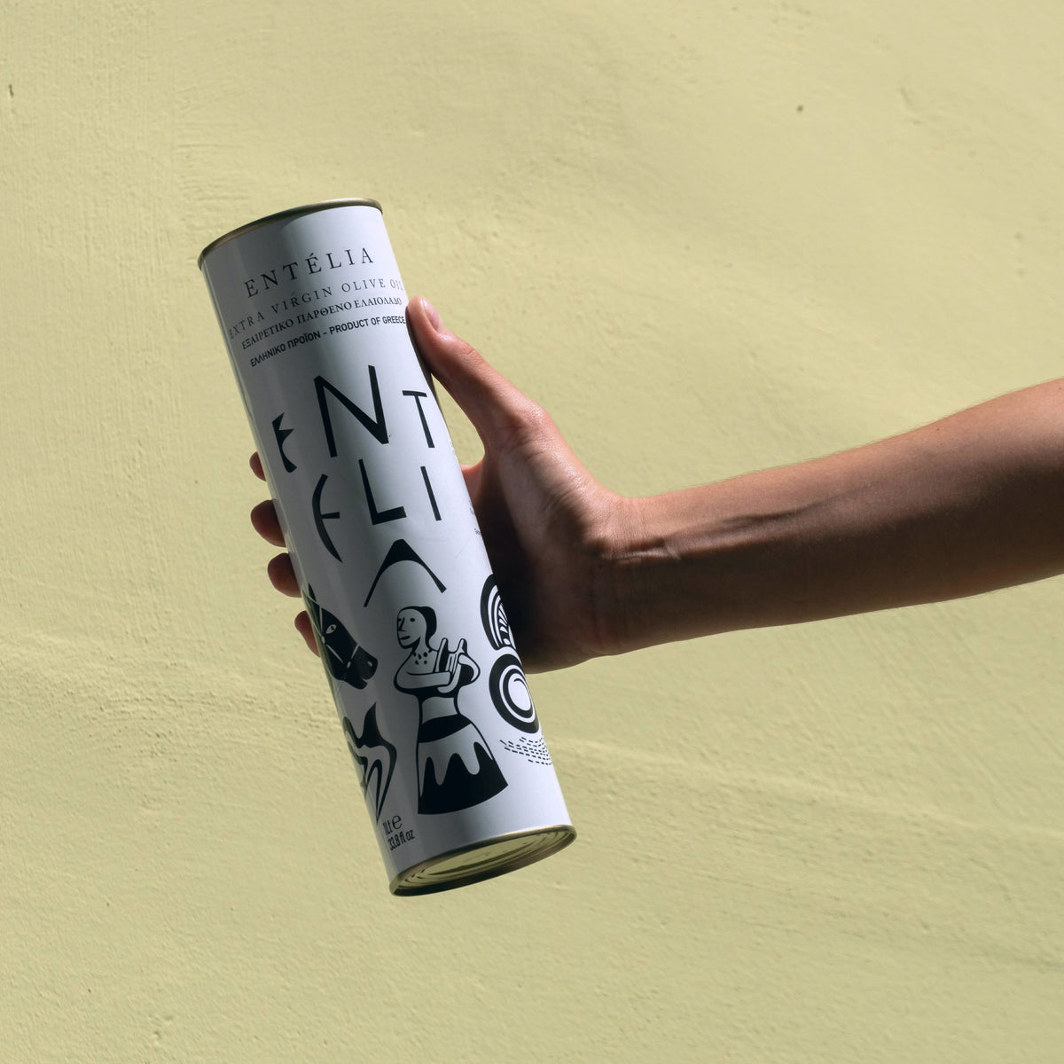 Holding an Entelia 1L extra virgin olive oil can from Crete, Greece.