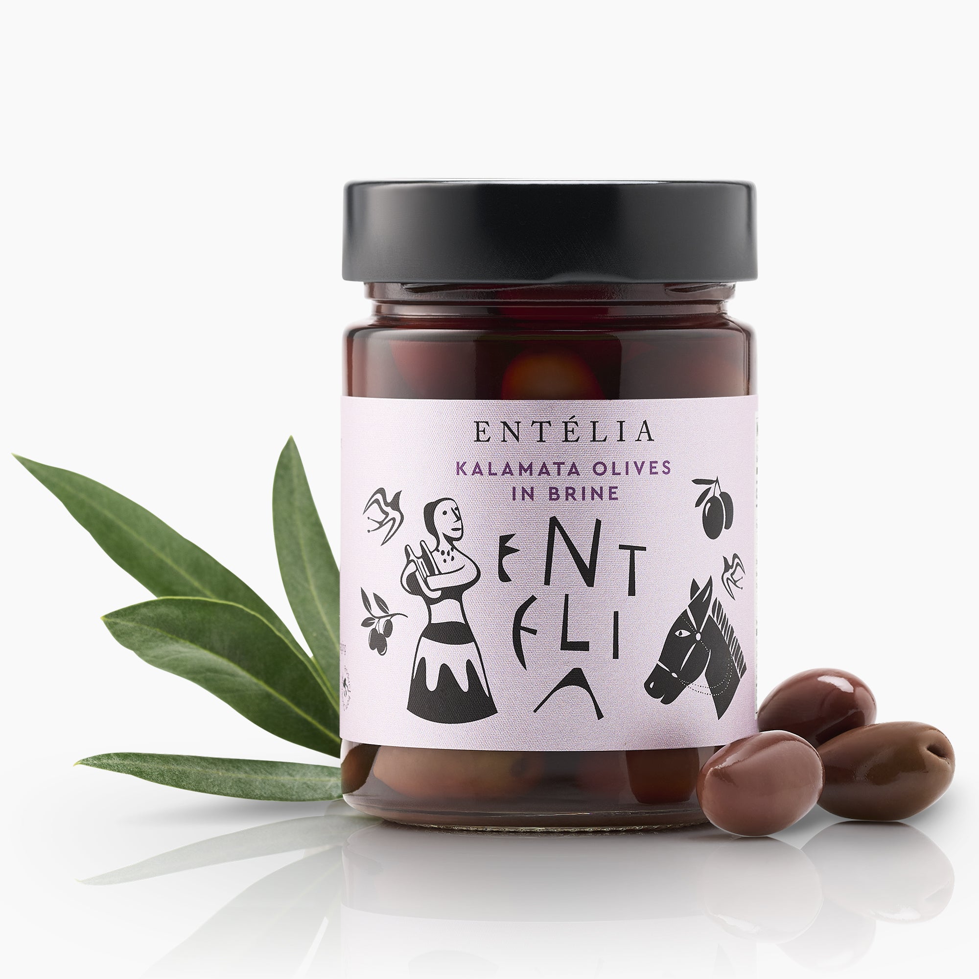 Entelia Kalamata Olives in Brine jar between three olives and green olive leaves.