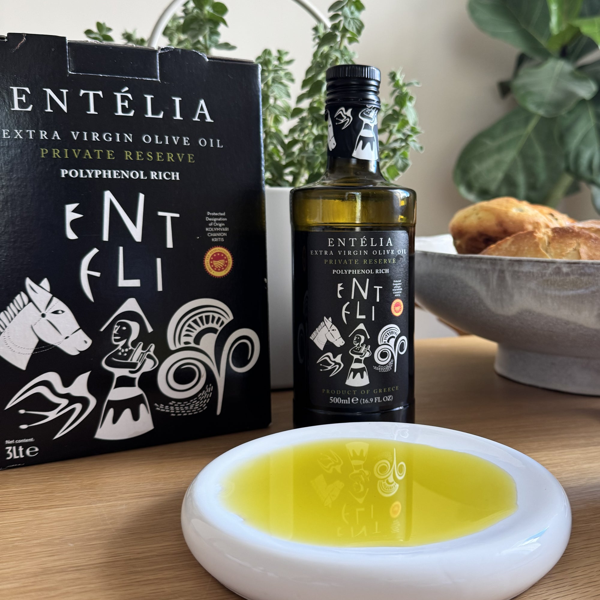 A 3L Bag-In-Box and a 500ml bottle of Entelia Private Reserve beside olive oil dish and bread.